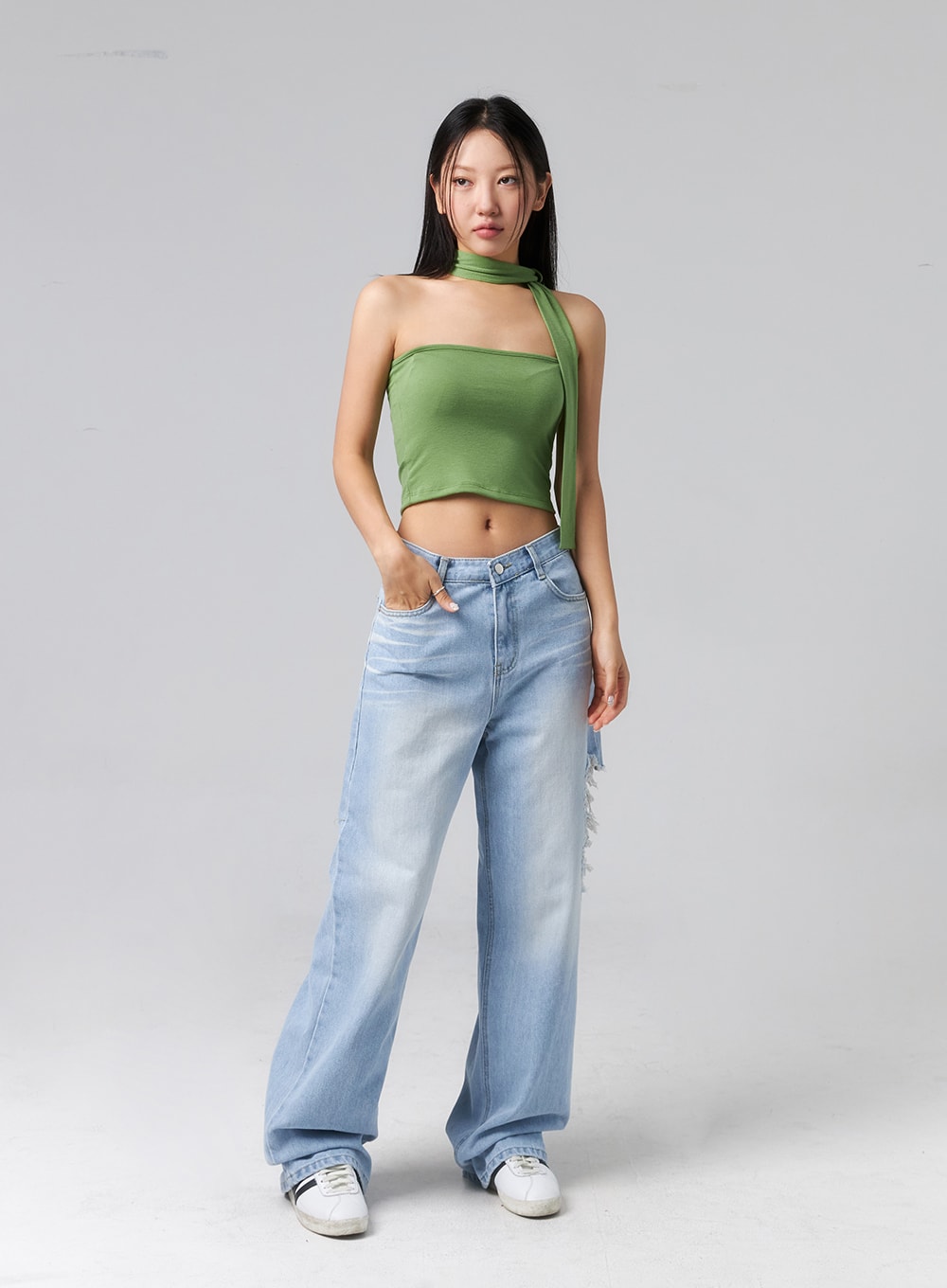 Ripped Side Jeans CL320 in light blue, front three-quarter view on model with hand in pocket, wide-leg faded denim with destroyed side tear, paired with green halter crop top.
