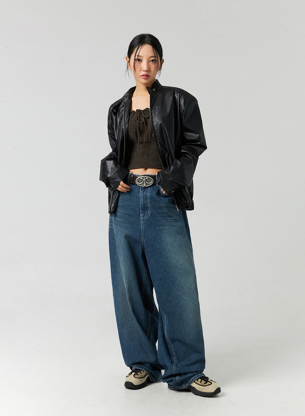 Washed Cotton Wide Leg Jeans CO323 in blue, full-body three-quarter front on model, washed wide leg denim with statement belt buckle, layered under open black leather jacket and knit crop top.