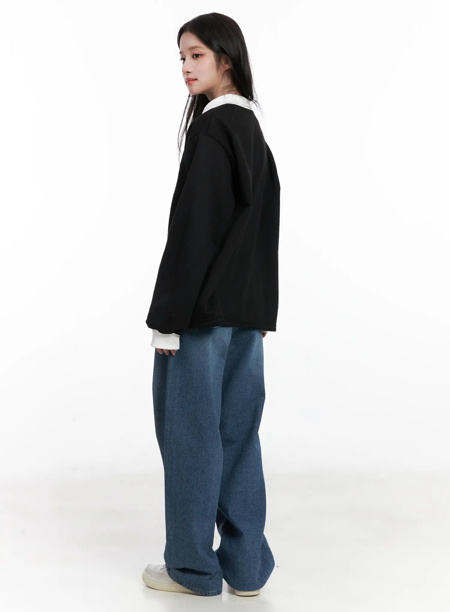 Mariam Baggy Jeans CN526 in blue, back-side view on model, relaxed wide-leg washed denim with roomy seat, styled with black polo sweatshirt and white sneakers.