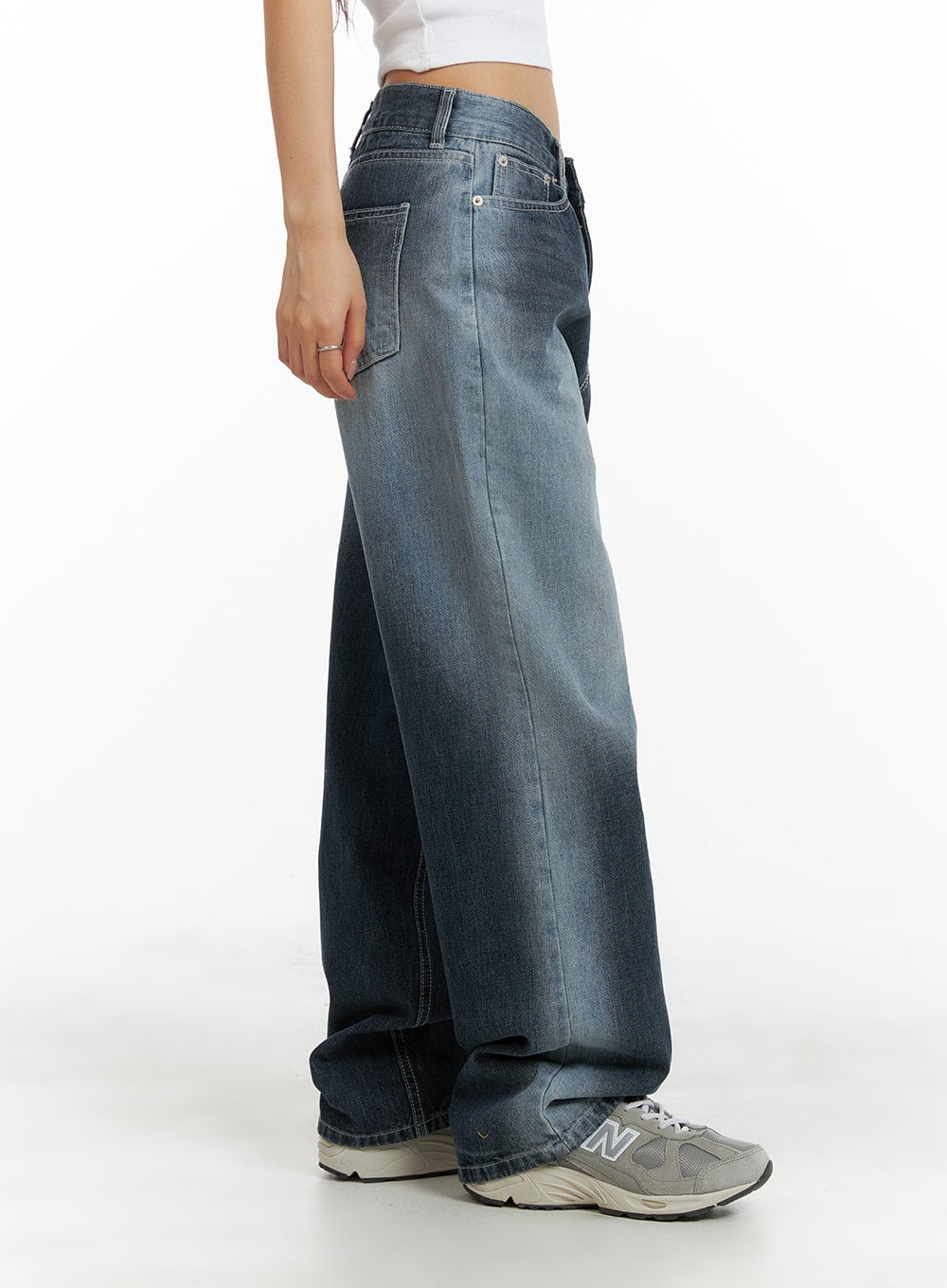 Recycled Wide Baggy Jeans (Unisex) CM425 in dark blue, side view on model, wide baggy leg silhouette with washed denim fade and contrast stitching detail, worn with New Balance sneakers.
