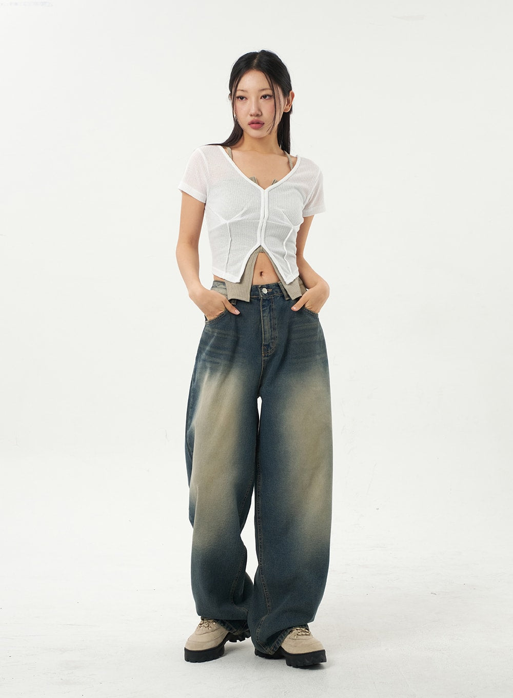 Mid-Rise Baggy Jeans CA325 in vintage blue denim, full-length front view on model with hands in pockets, wide-leg cotton denim with sun-bleached gradient wash, paired with white sheer crop top.