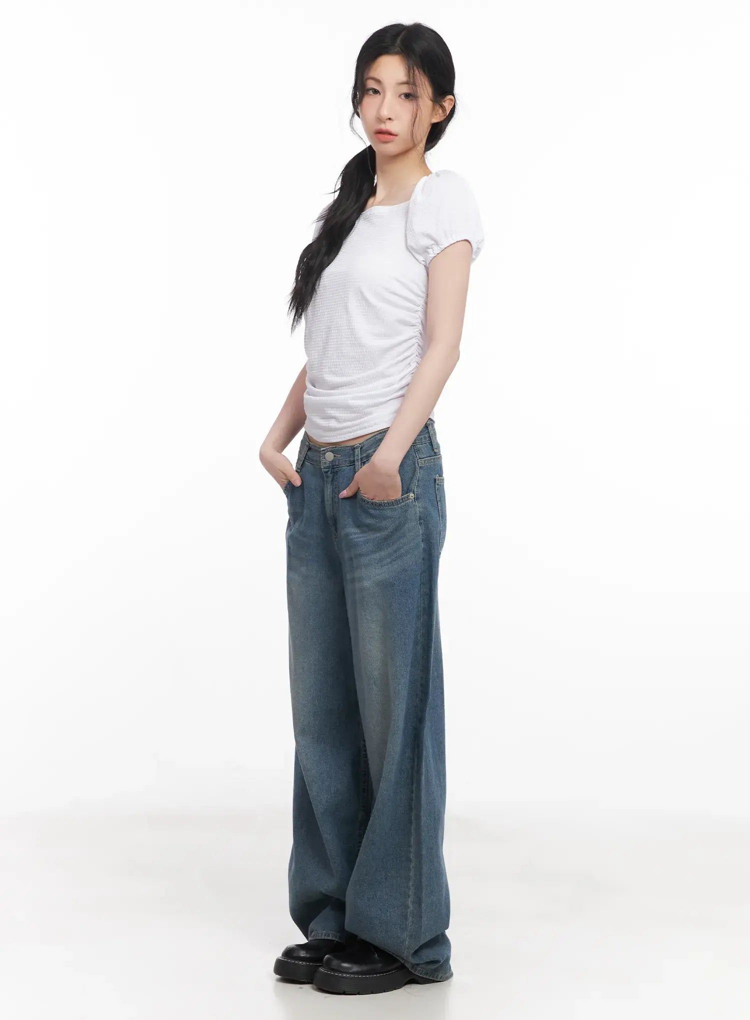 Chaewon Washed Wide-Leg Jeans CU511 in blue, side view on model with hands in pockets, wide-leg silhouette pooling at hem, paired with white ruched crop tee and black loafers.