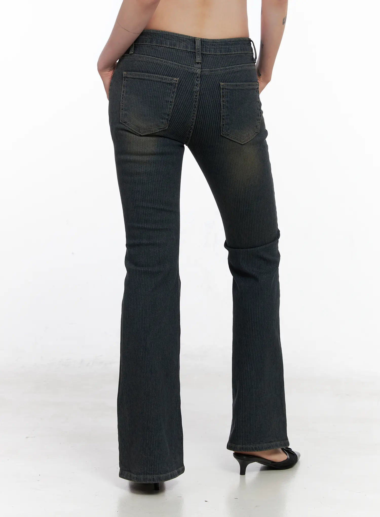 Soleil Hip Pad Stripe Hip Pad Flared Jeans CN512 in dark blue, back view on model, washed stripe bootcut showing dual back pockets and hip pad curve, low rise waistband, flared long hem, black kitten-heel mules.