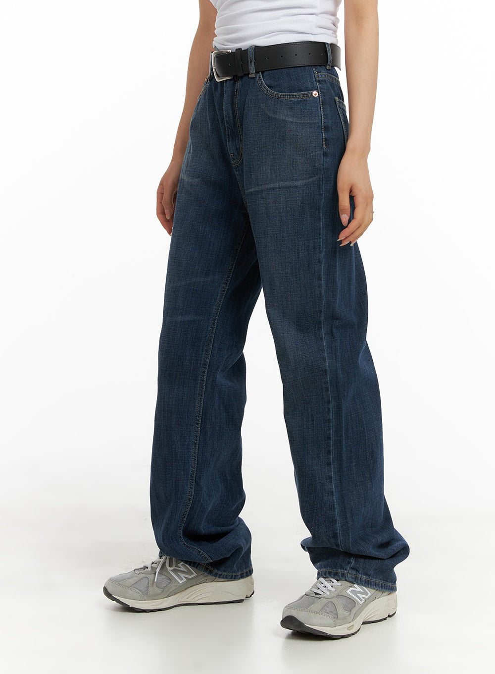 Washed Straight Jeans CA408 in dark blue, side angle view on model, straight-leg silhouette with washed cotton denim, belted waist, worn with white tee and grey New Balance sneakers.