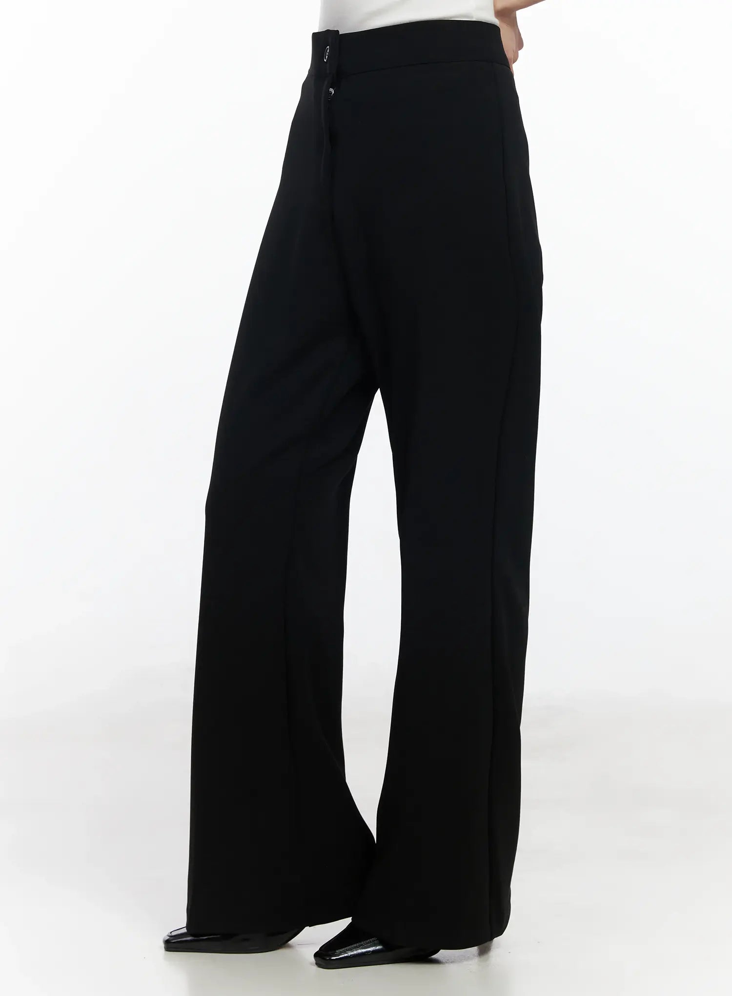 Hip Pad Slacks IJ529 in black, side-angle view on model, hip pad detail and side button visible, bootcut flare, high-rise waistband, heeled shoes.
