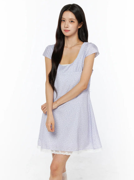 Romantic Floral Lace Trim Mini Dress CU522 in light purple, front three-quarter view on model, scoop neckline with gathered cap sleeves, floral print fabric, cream lace trim at hem, delicate necklace.