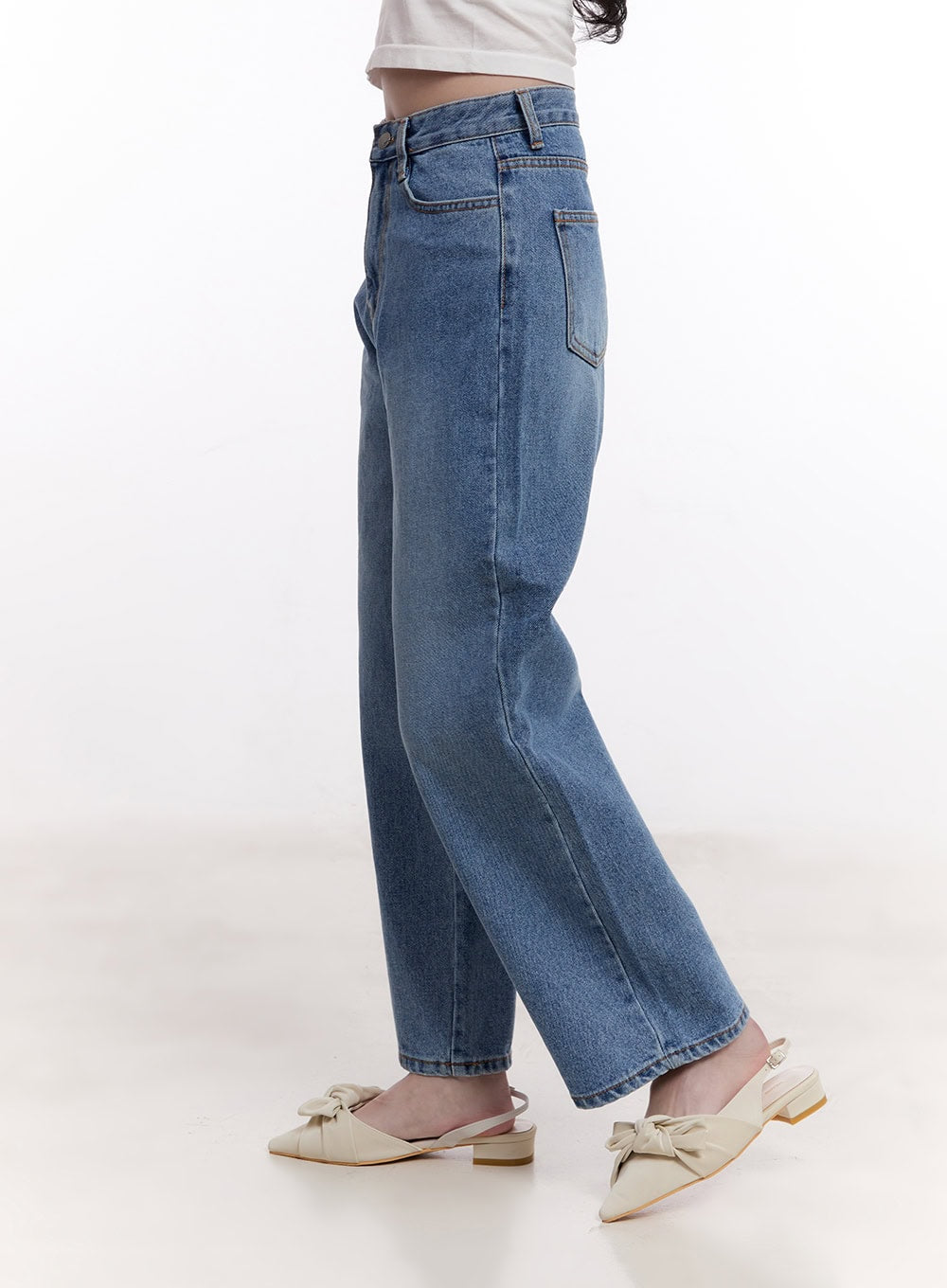 Jamie Comfy Straight-Fit Jeans CM526 in mid-blue wash, side view on model mid-stride, high-rise straight-fit cotton denim with front pocket stitching, styled with bow-detail mules.