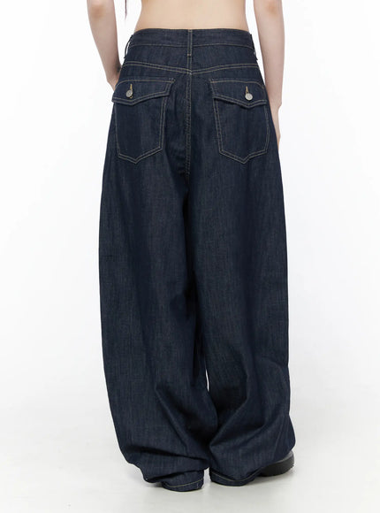 Rowen Baggy Jeans CU519 in dark blue, back view on model, featuring two flap pockets with round metal buttons, contrast stitching on waistband, voluminous leg pooling at hem.