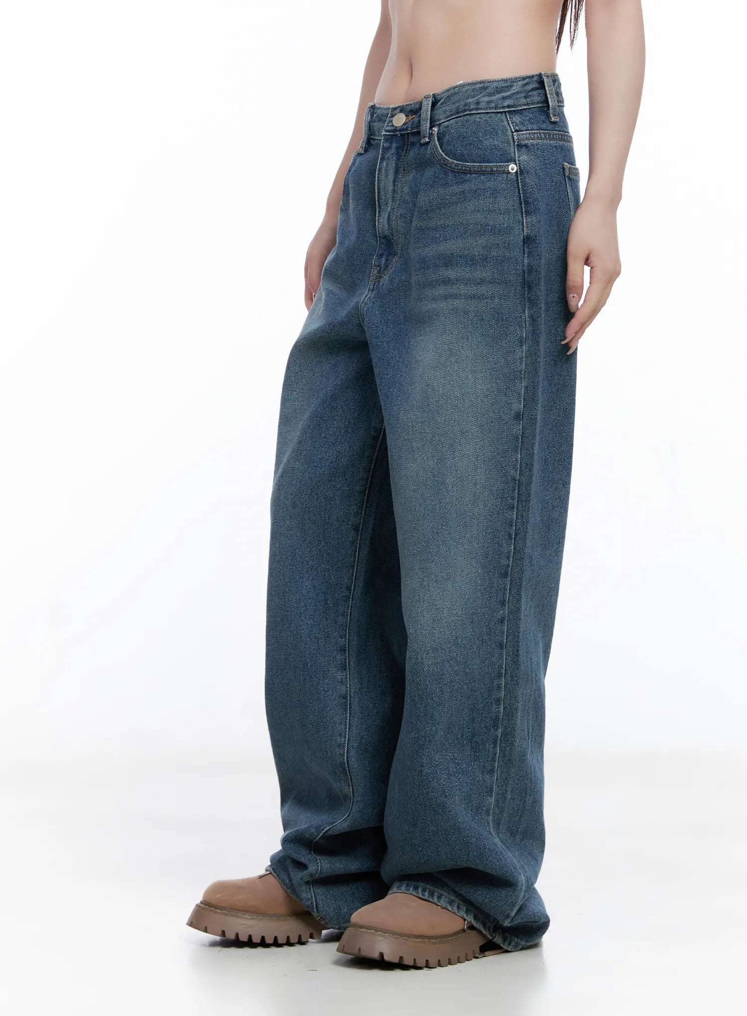 Amalia Wide Leg Vintage Washed Jeans CG529 in blue, side view on model showing wide-leg silhouette, faded wash shading, loose fit through hip and thigh, pooling at chunky brown boots.