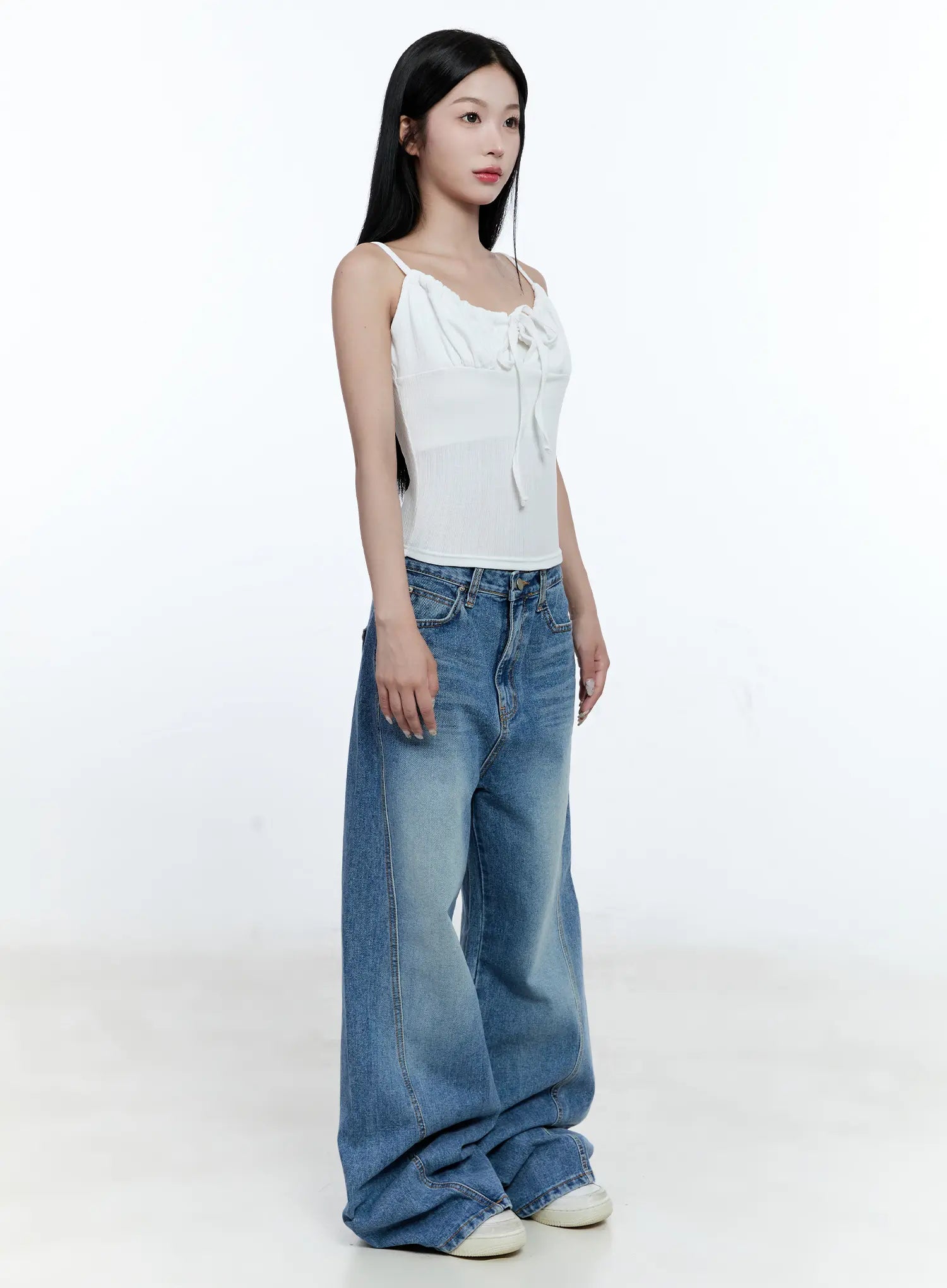 Ana Wide-Leg Denim Jeans CG507 in blue, three-quarter front angle on model, washed wide-leg silhouette styled with white tie-front cami, showing volume and seam detail.