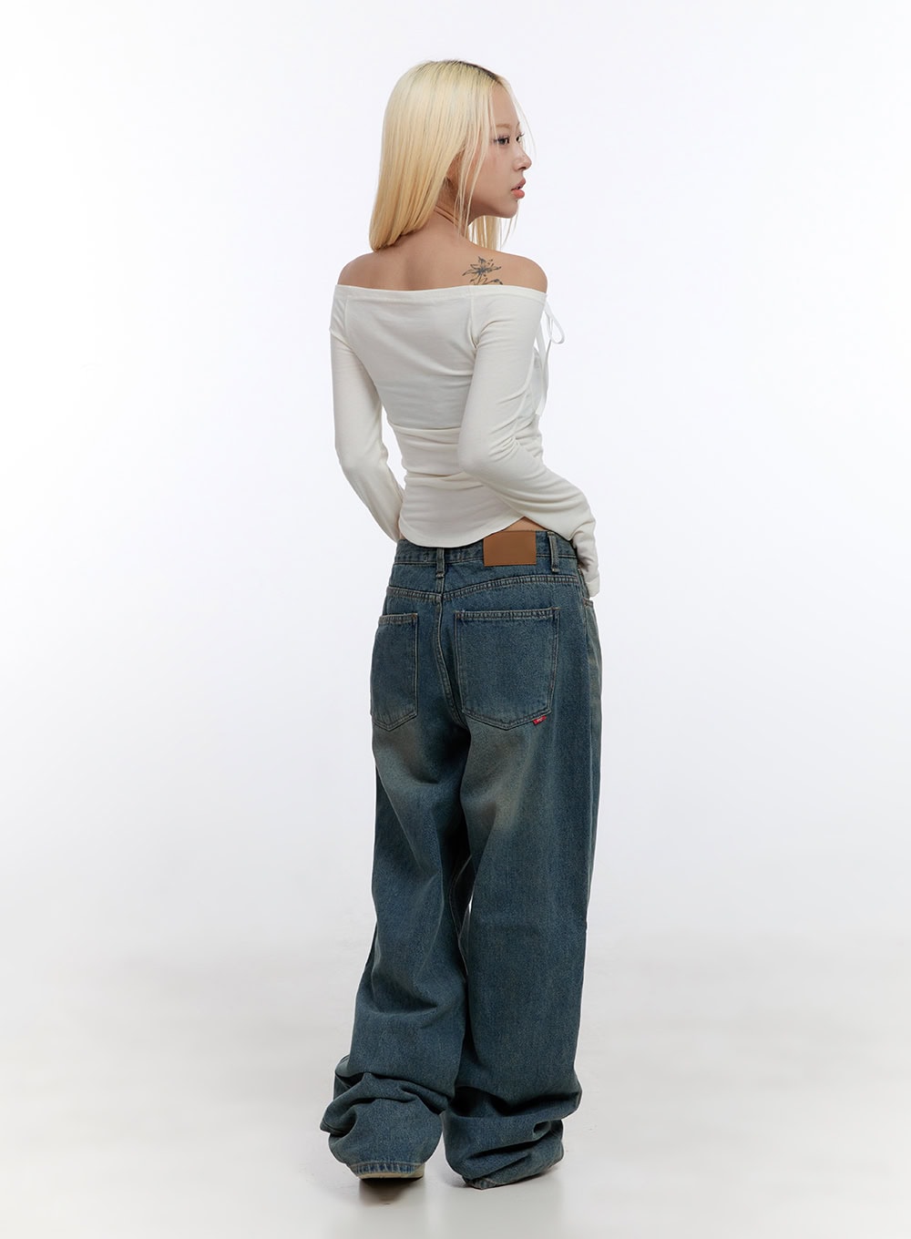 Zola Casual Fit Denim Jeans CO422 in blue, full-length back view on model, showing leather patch waistband label and wide baggy leg, paired with white off-shoulder top and sneakers.