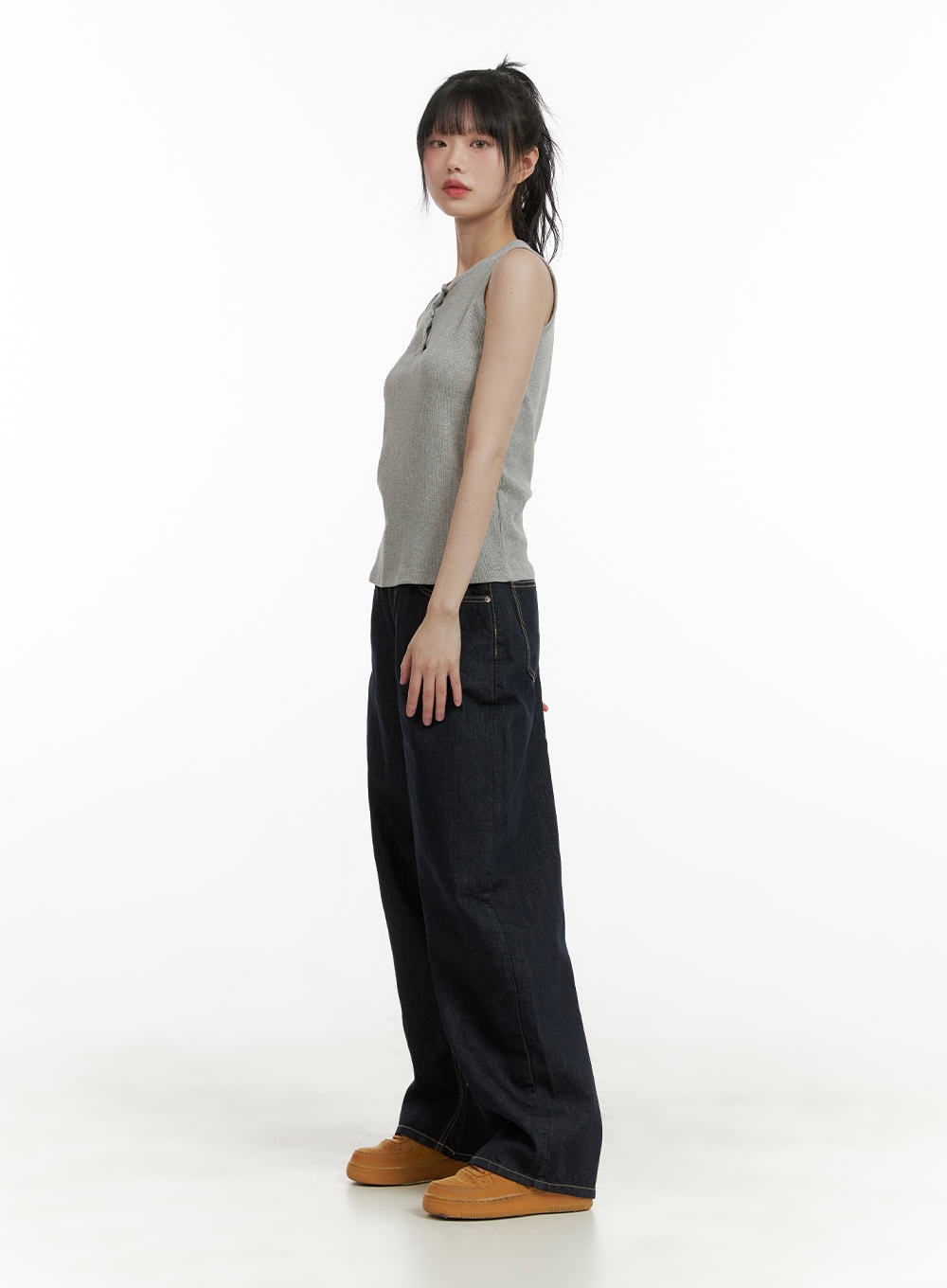 Stitch Detail Baggy Jeans CU410 in dark blue, angled side full-body view on model, wide-leg cotton denim with contrast stitching, worn with grey sleeveless top and tan sneakers.