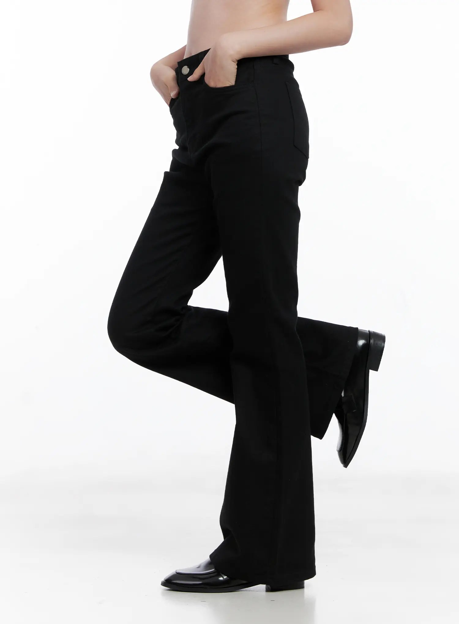 Casual Flare Cotton Pants CG521 in black, side view on model with leg raised, showing flare silhouette, high waist, side pocket, and bootcut hem with black loafers.