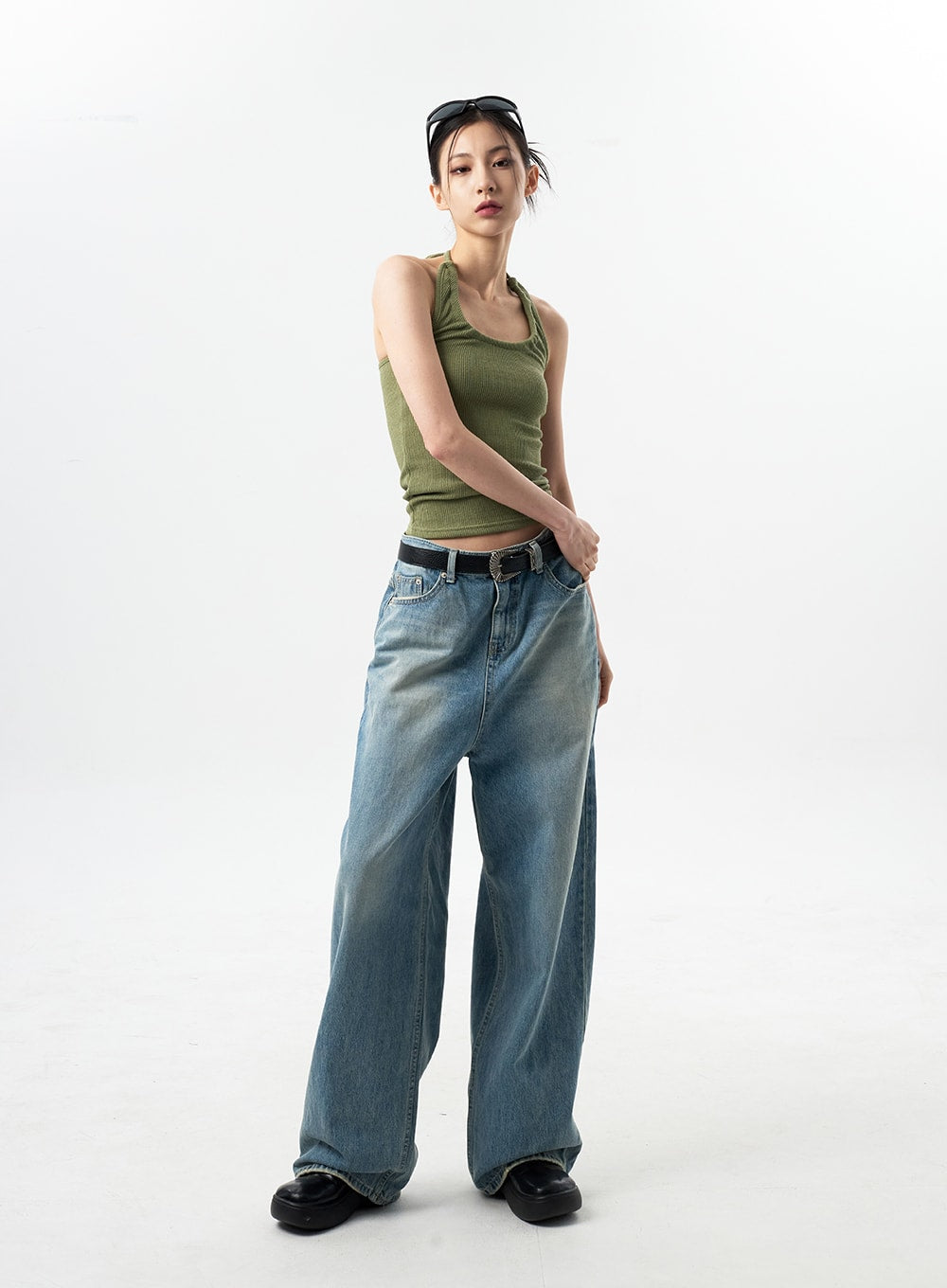 Oversized Jeans Unisex CY312 in washed blue, full-length angled front view on model, wide-leg casual denim with vintage wash, paired with green halter top and belt.