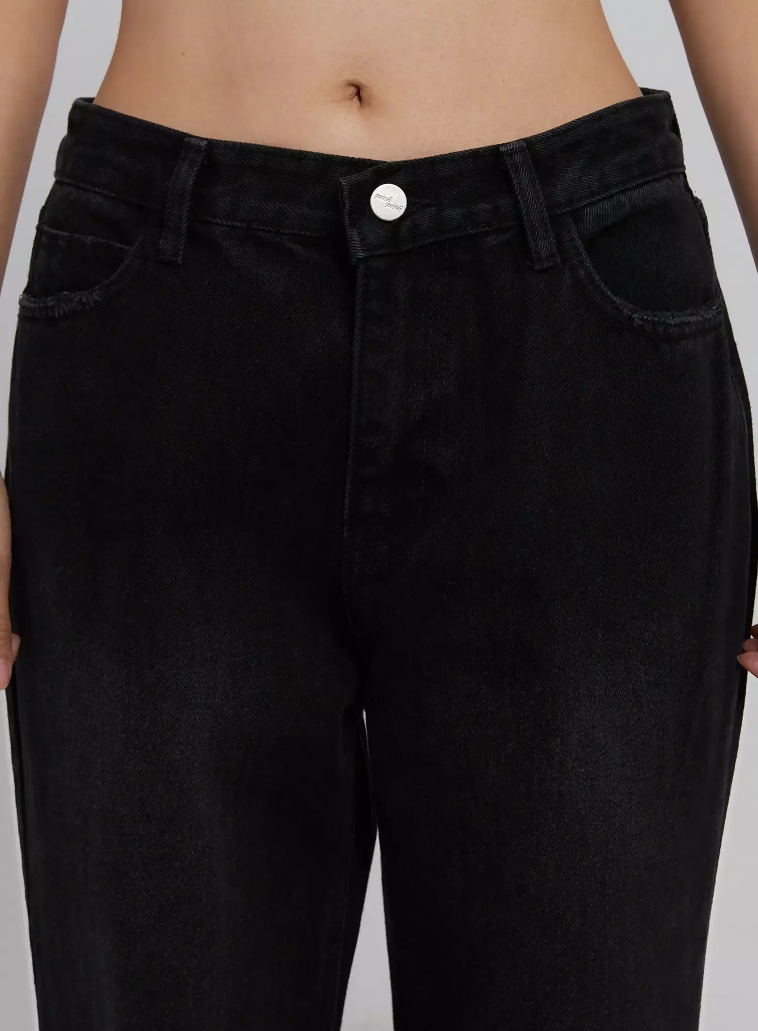 Imani Wide-Leg Flared Jeans ID516 in black, close-up front detail on model, highlighting waistband, silver button, zip fly, front pockets with contrast stitching, faded cotton denim texture.