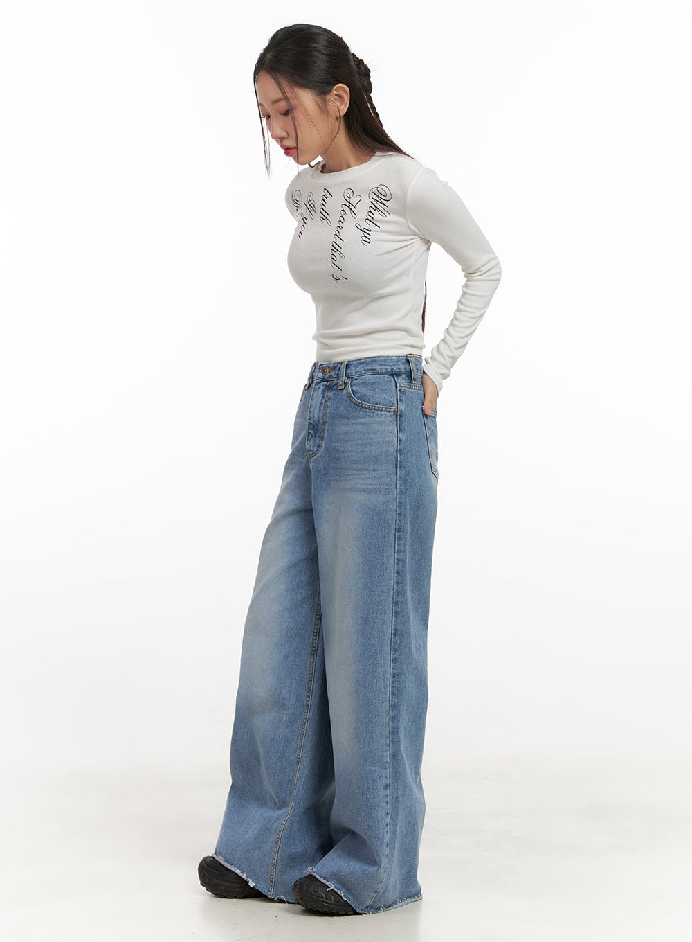 Melody Chic Flare Wide Leg Jeans CN428 in light blue, angled side view on model looking down, washed denim with wide flare leg and frayed hem detail, paired with white graphic crop top and black sneakers.