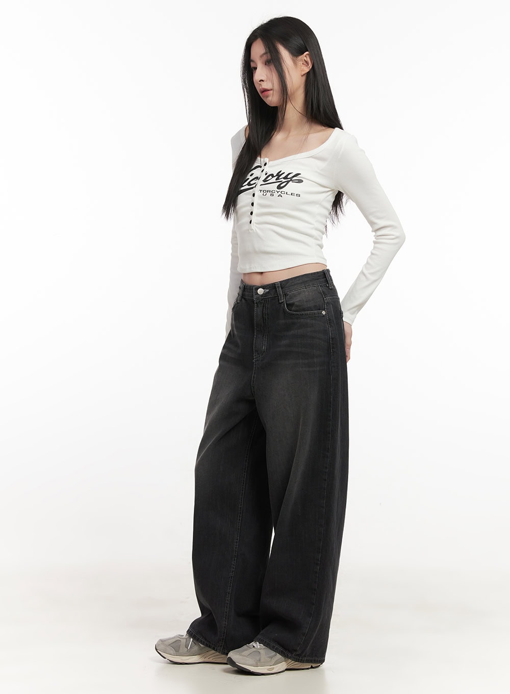 Ruth Washed Wide-Leg Jeans CF514 in black, side view on model looking down, wide-leg drape and mid-rise waistband visible, styled with white graphic crop top and sneakers.