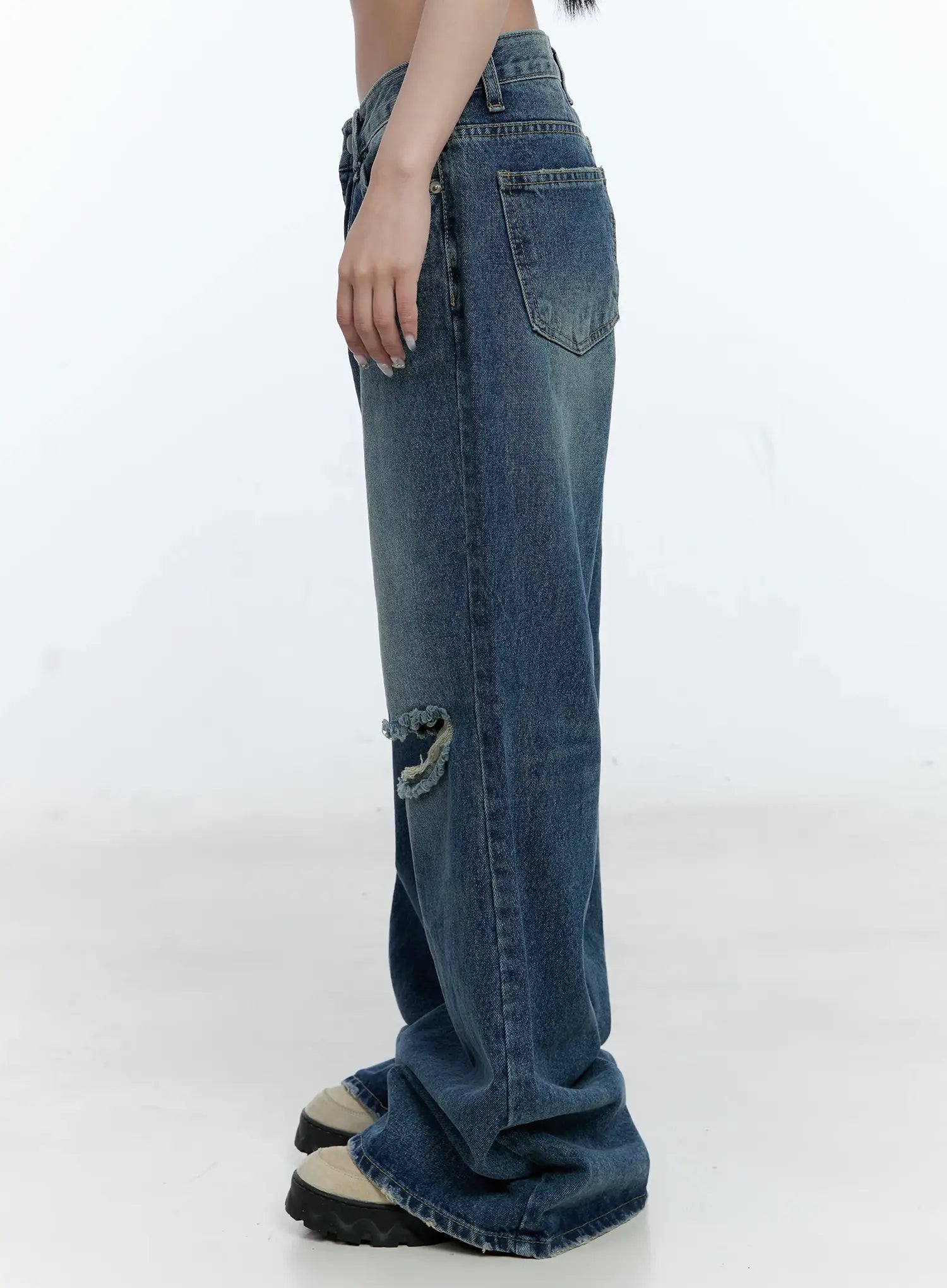 Gabi Distressed Semi-Flared Denim Jeans CG501 in dark blue, side view on model, showing back pocket, knee destruction, washed fade, and flared hem stacking at floor.