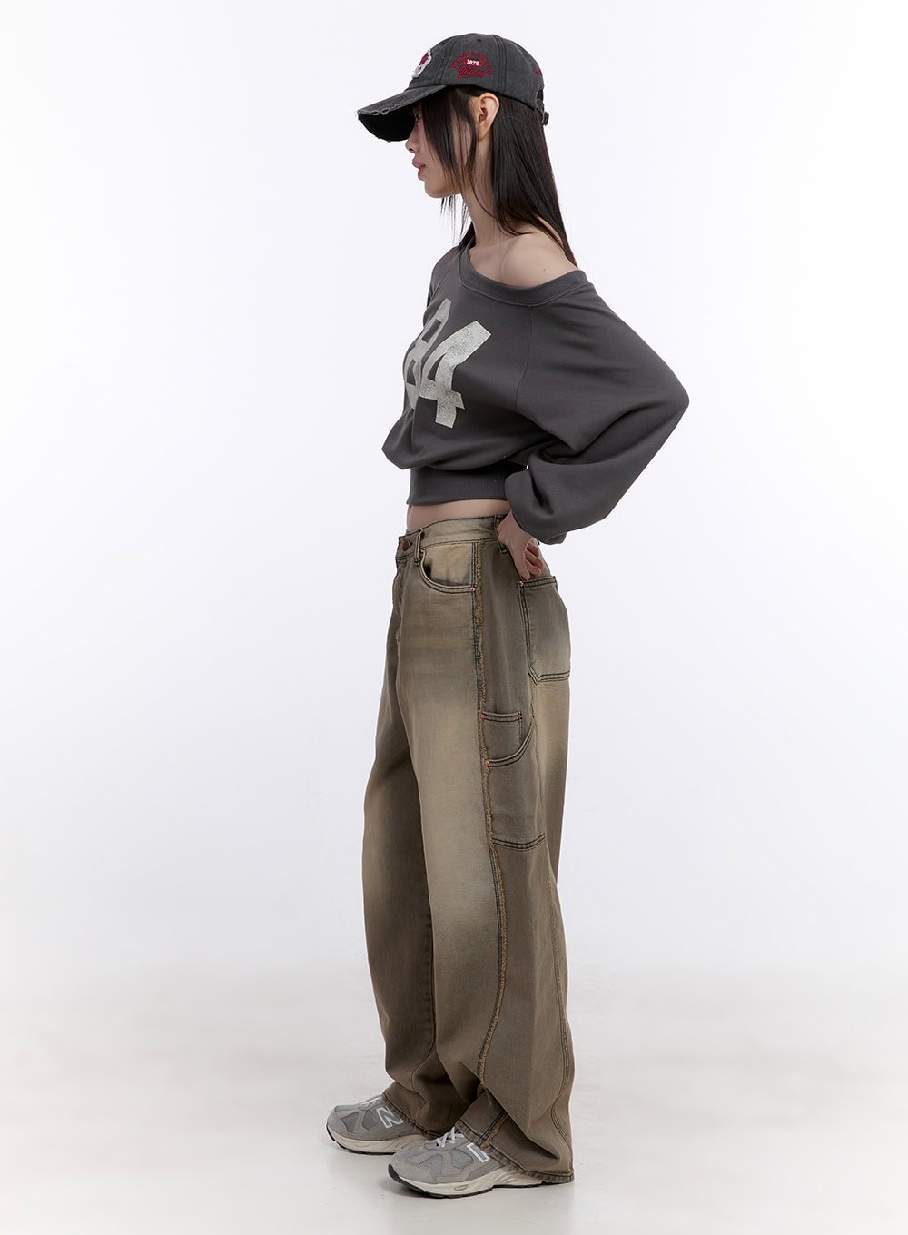 Sara Stitched Pocket Baggy Jeans CF512 in Beige, side view on model, wide-fit washed denim highlighting stitched side pockets and panel seams, styled with grey crop top and cap.