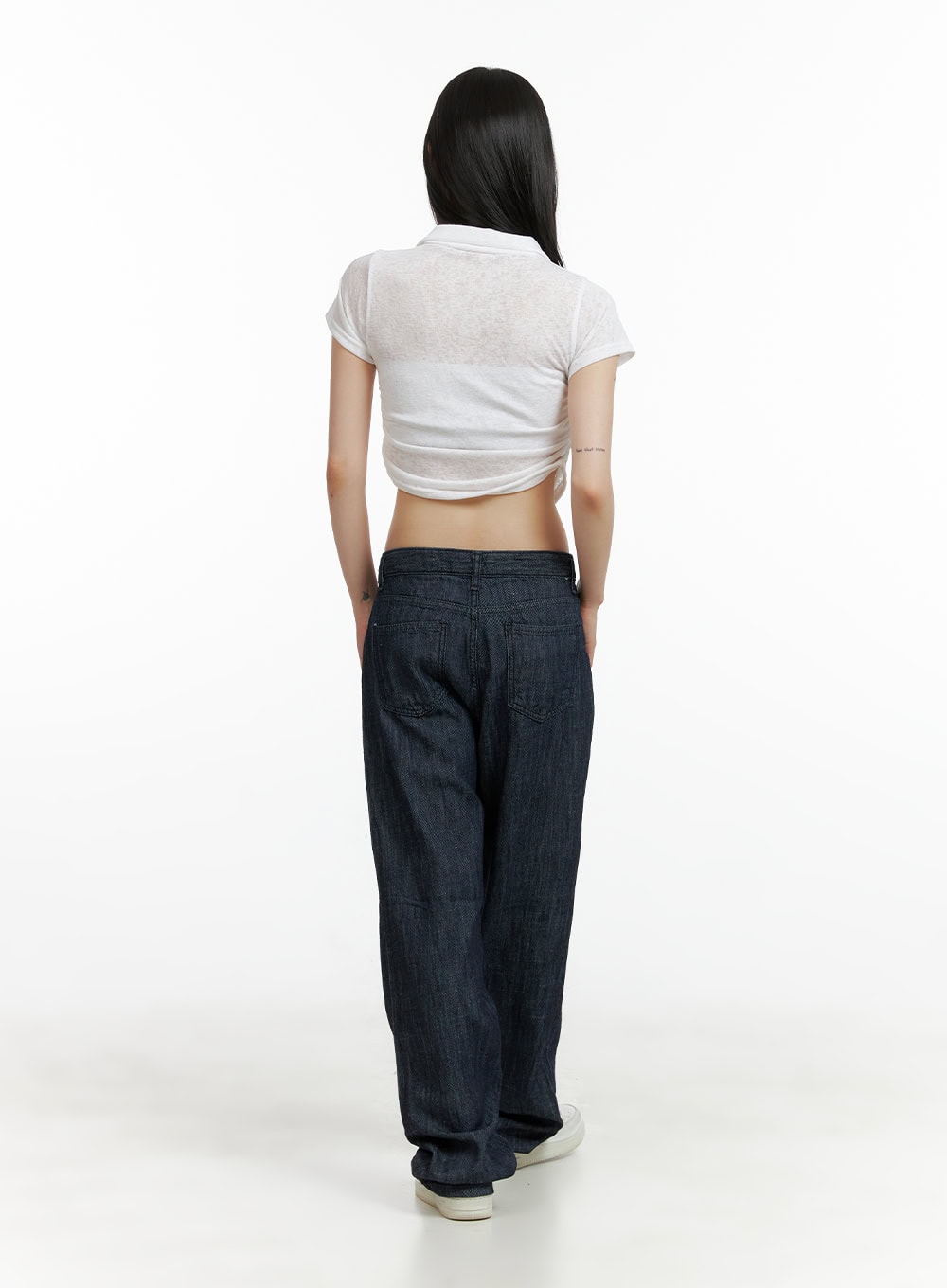 Low Waist Loose Fit Baggy Jeans CL403 in dark blue, back full-length shot on model, back patch pockets visible, baggy wide-leg cotton denim, with white crop top and sneakers.