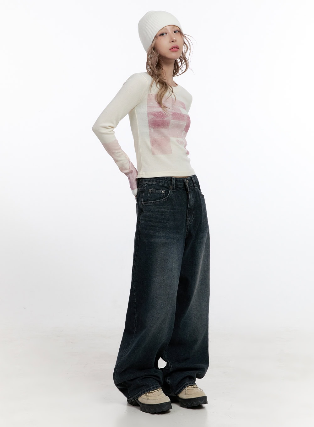 Camila Washed Cotton Jeans CN422 in dark blue, three-quarter front view on model, oversize wide-leg washed denim, hand on hip pose, styled with cream graphic top and white beanie.