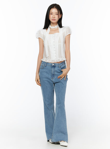 Leana Stretch Bootcut Jeans IU519 in blue, full-length front view on model, normal fit with gentle flare at hem, styled with white sheer ruffle top and white flats.