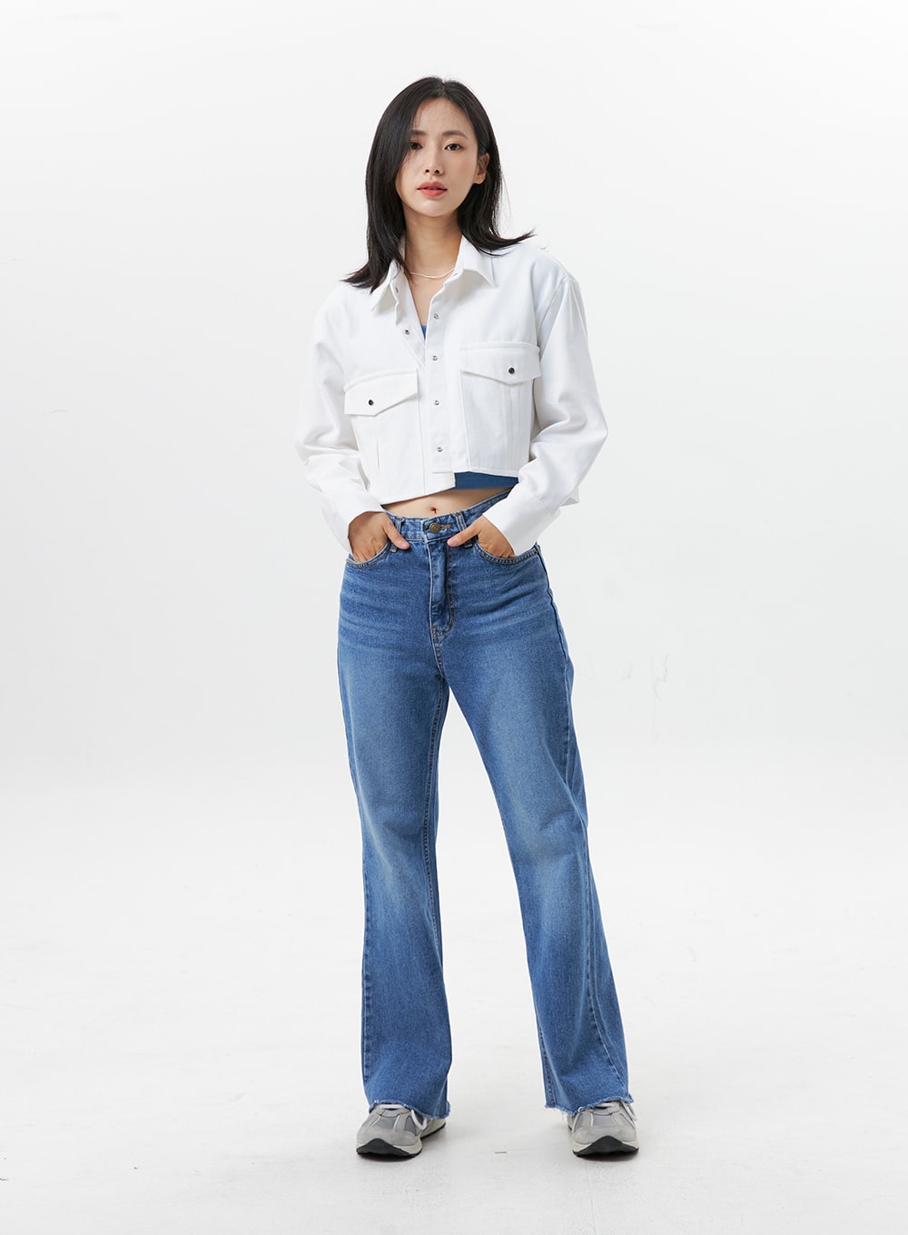 Straight-Leg Jeans OG318 in medium blue, front full-length on model, hands in pockets pose, high-rise cotton denim, straight fit with slight bootcut flare, raw cut hem, white cropped jacket over.