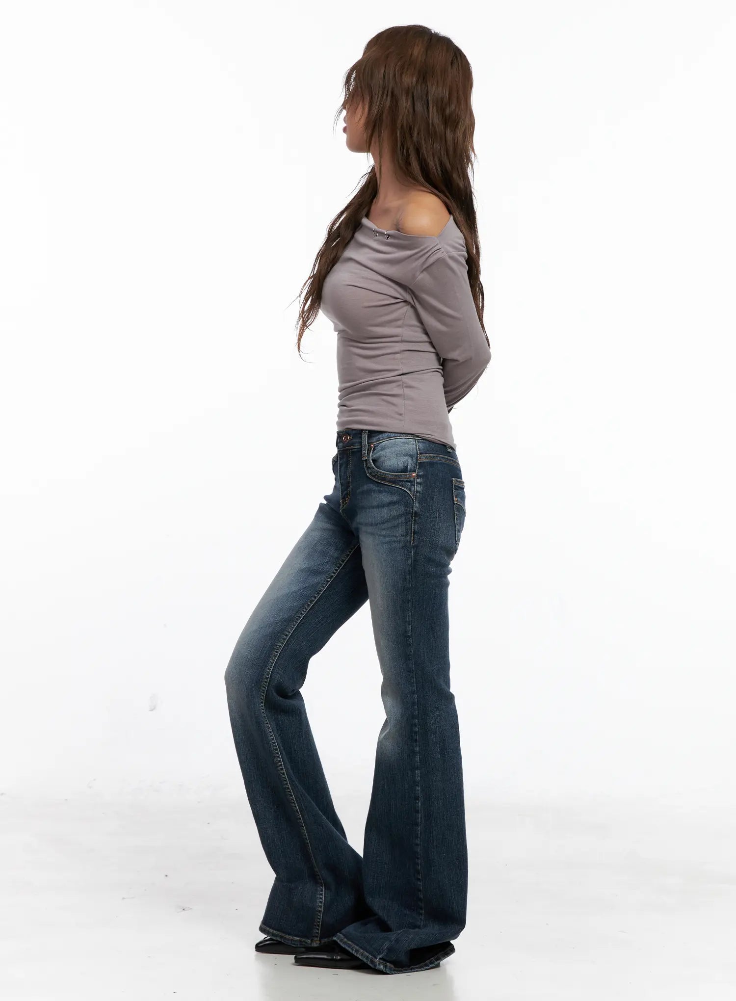 Saanvi Vintage Wash Flare Jeans CS522 in dark blue, side profile full-length shot on model, paired with grey off-shoulder top, flare hem pooling at floor, wide-fit silhouette highlighted.