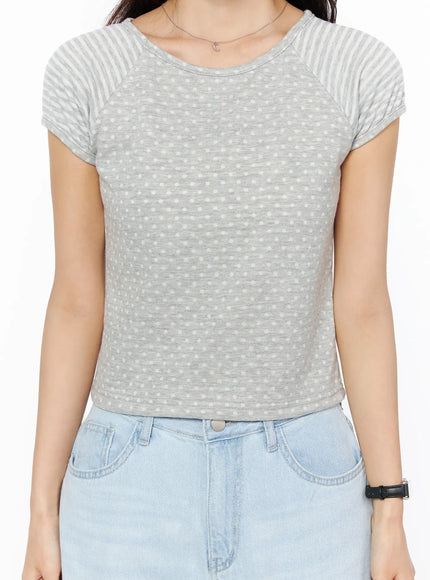 Polka Dot Striped Crop Tee CU522 in gray, close-up front torso shot on model, white polka dot body fabric and contrast stripe raglan sleeves, round neckline, cropped hem.
