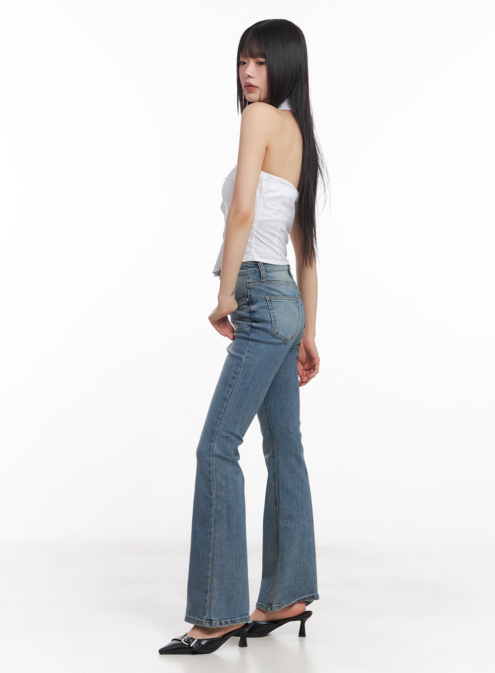 Cassy Slim Washed Flared Jeans CY512 in blue, three-quarter side view on model, showing slim hip and flared hem silhouette, paired with white halter top and black kitten-heel mules.