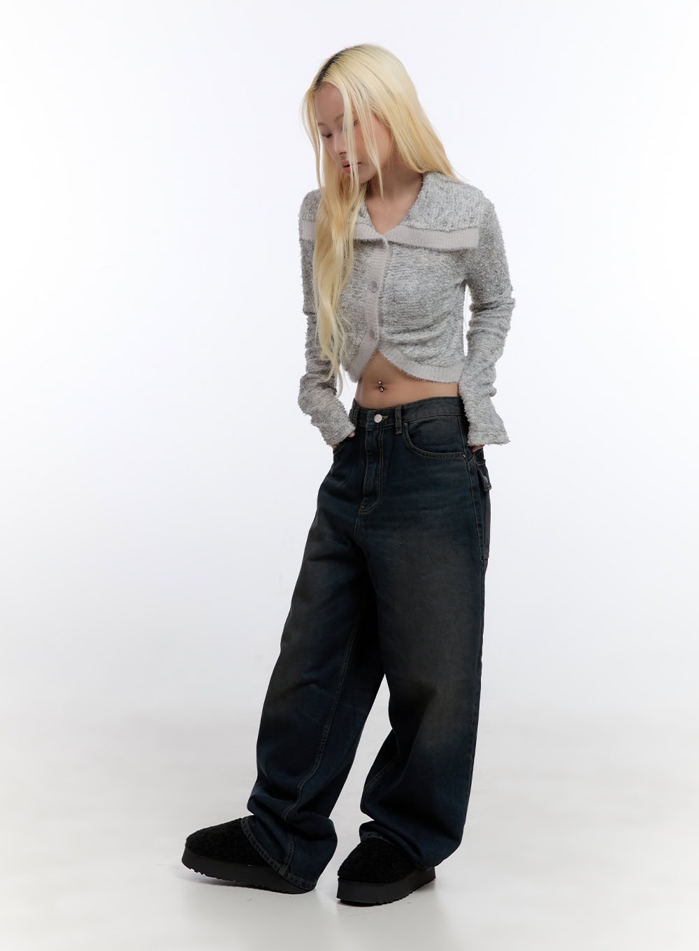 Lyla Wide Leg Jeans CO423 in dark blue, three-quarter front angle on model looking down, relaxed wide-leg washed denim paired with grey cropped knit cardigan.