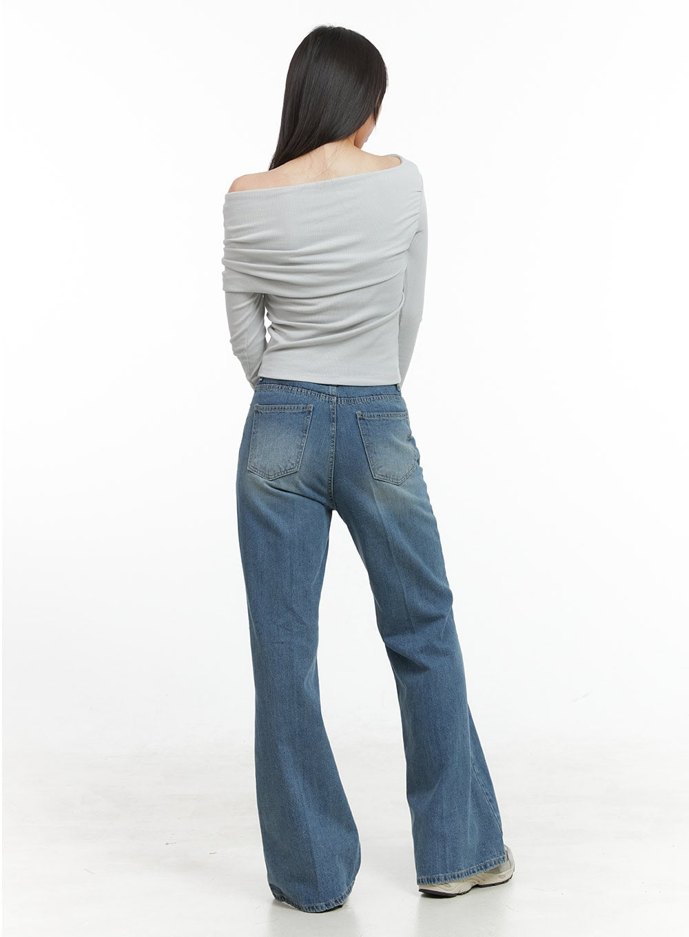 Daisy Loose Fit Bootcut Jeans CG419 in blue, back full-body shot on model, washed denim with two back patch pockets and flared bootcut hem, styled with grey top.