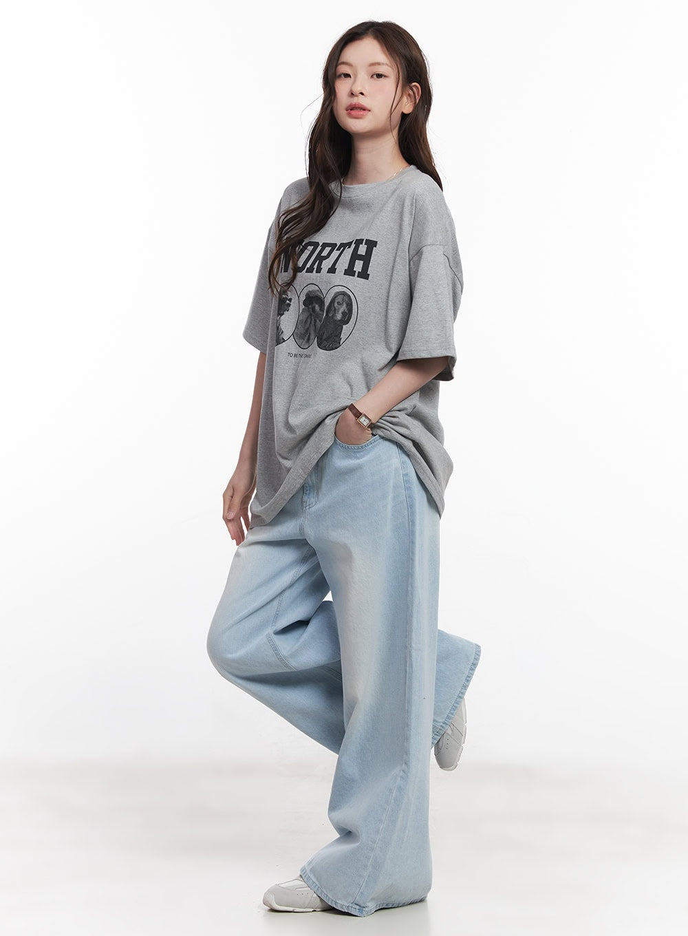 Judie Washed Wide-Leg Jeans CY519 in light blue, side-angled full-body shot on model with one leg raised, wide washed denim, paired with gray graphic tee and white sneakers.