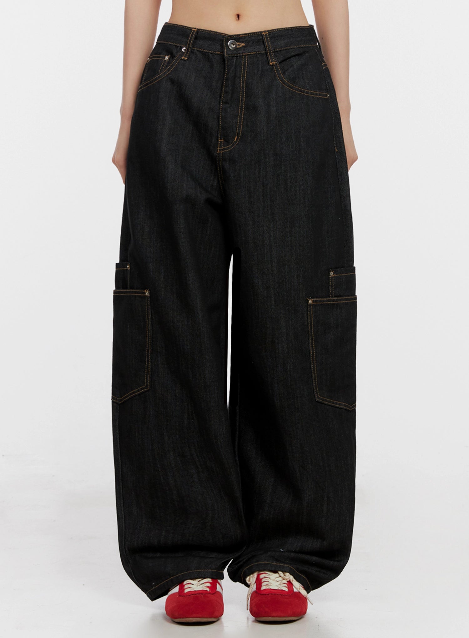 Dahee Wide-Leg Cargo Jeans IG508 in black, front view on model cropped at waist, wide-leg cotton denim with contrast stitching, front pockets and side cargo pockets visible, paired with red sneakers.