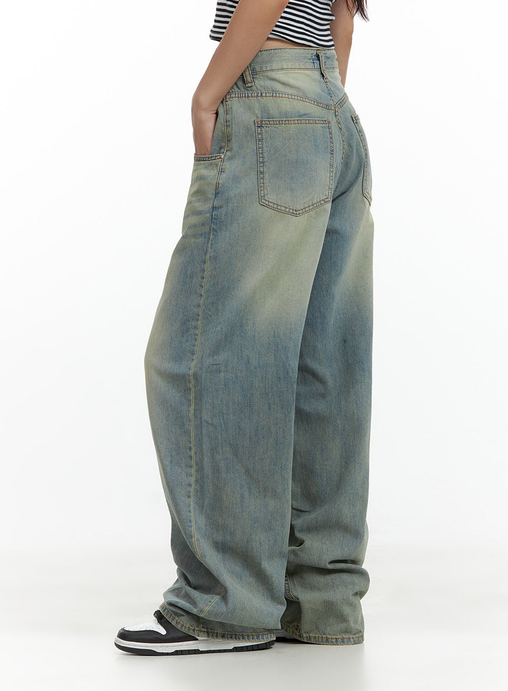 Relaxed Wide-Leg Jeans CU420 in blue, side close-up on model, back pocket detail with contrast topstitching, washed denim with yellowish fading, baggy wide leg, paired with stripe crop top.