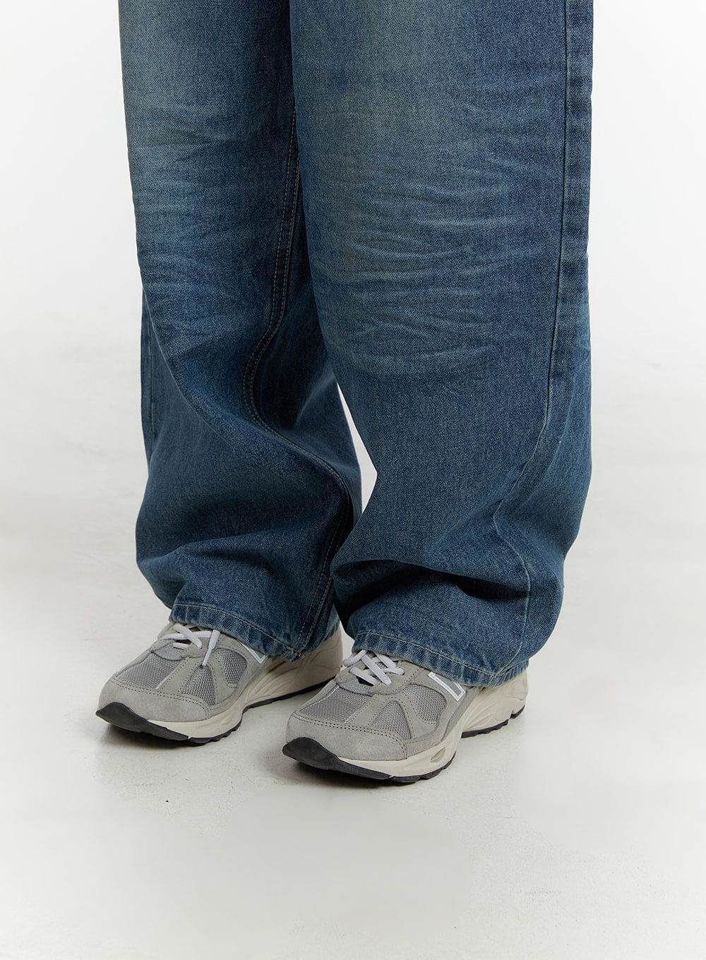 Wide Fit Baggy Jeans CA401 in blue, lower-leg close-up on model, showing extra-wide hem stacking over grey sneakers with washed denim crease texture.