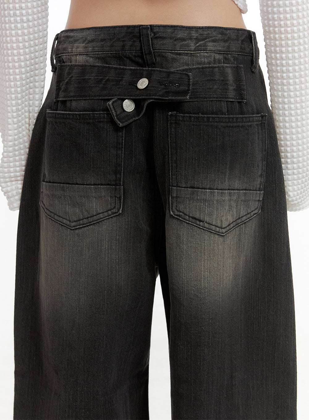 Sage Back-Buttoned Wide Pants CS430 in black, back waistband close-up on model, showing signature back button closure with silver button detail, patch back pockets, and washed denim texture.