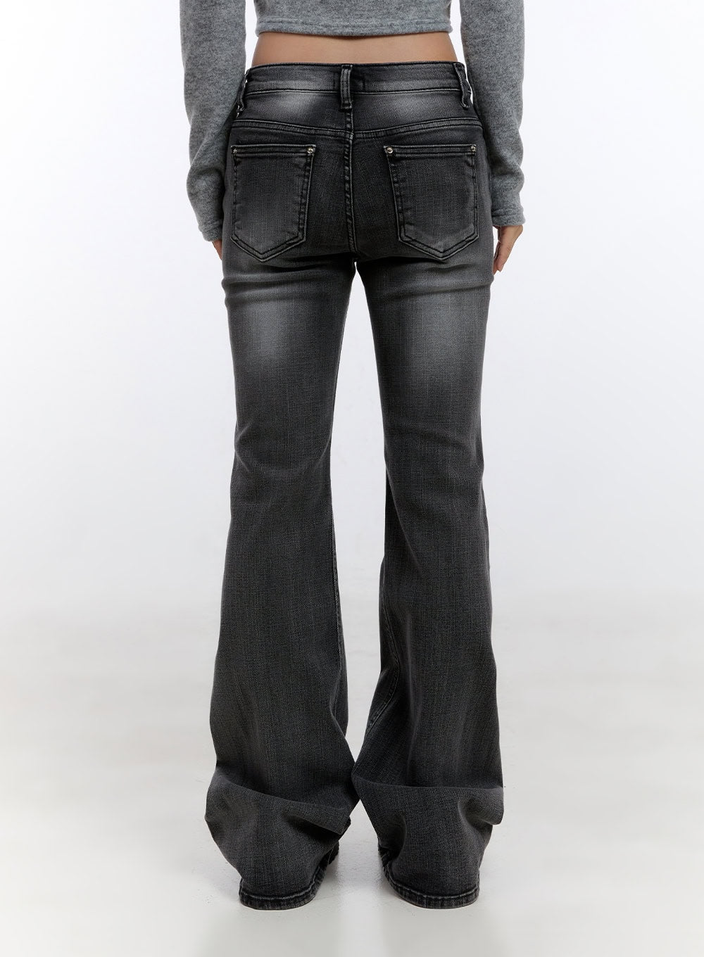 Gianna Faded Flared Jeans CO422 in Black, back view on model, washed denim with dual back pockets and flared bootcut hem pooling at floor, styled with grey crop top.