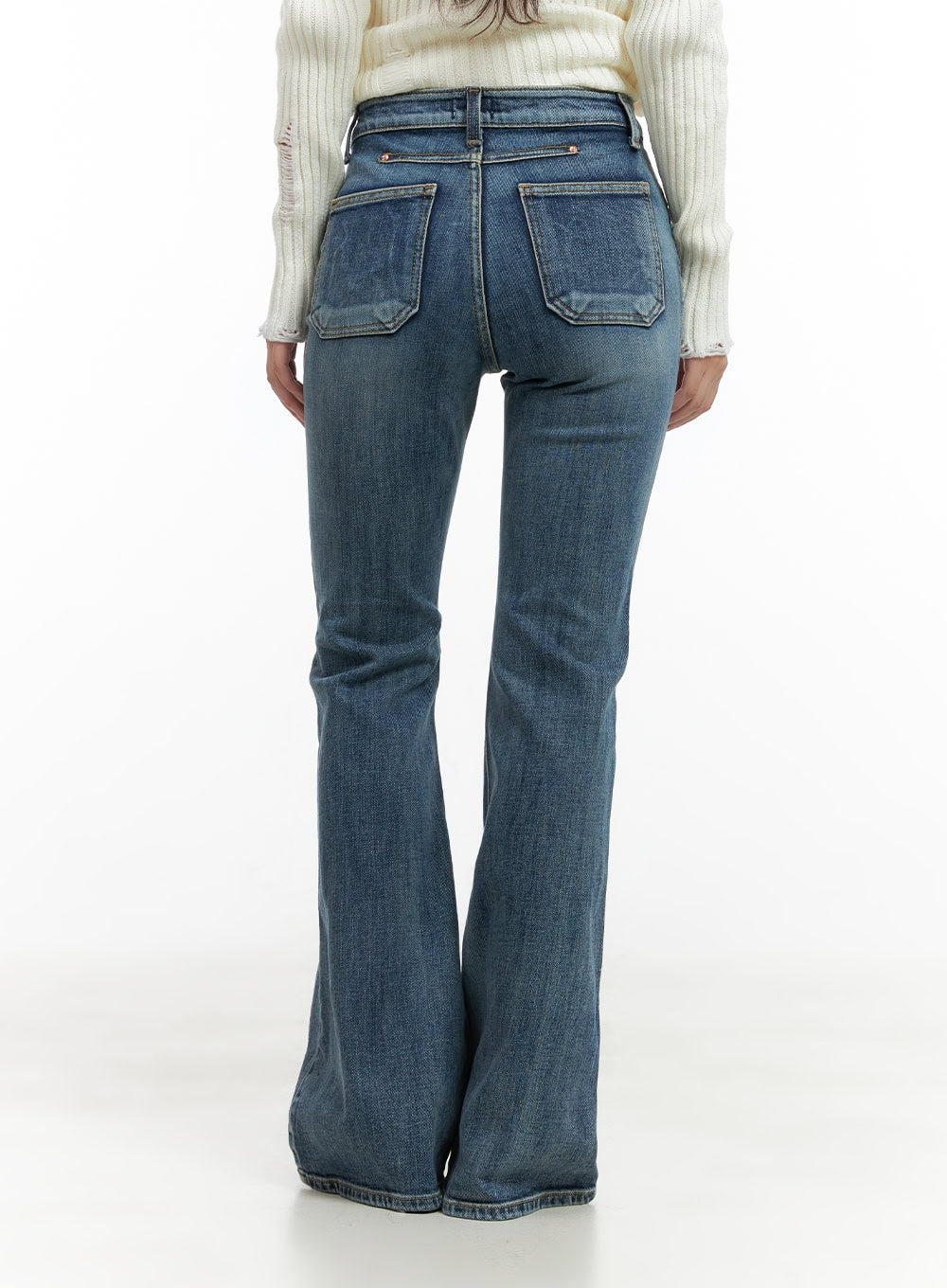 Lila Slim Bootcut Jeans CG422 in blue, back close-up on model, washed denim showing dual back patch pockets with copper rivets and bootcut flare hem, paired with white ribbed knit.