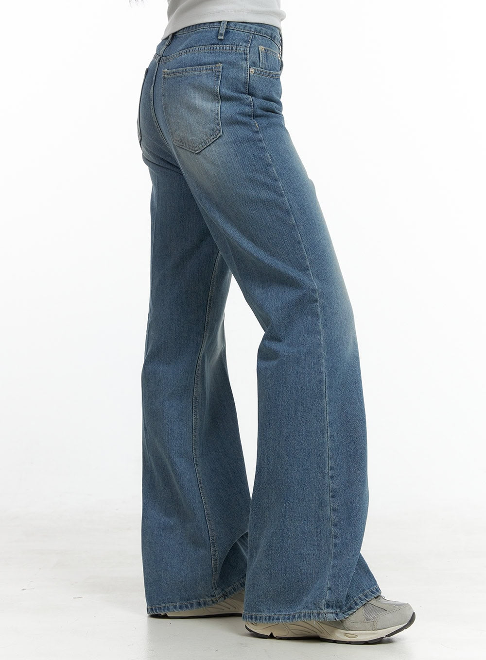 Daisy Loose Fit Bootcut Jeans CG419 in blue, rear three-quarter close-up on model, showing washed denim texture, back pocket detail and wide bootcut flare with sneakers.