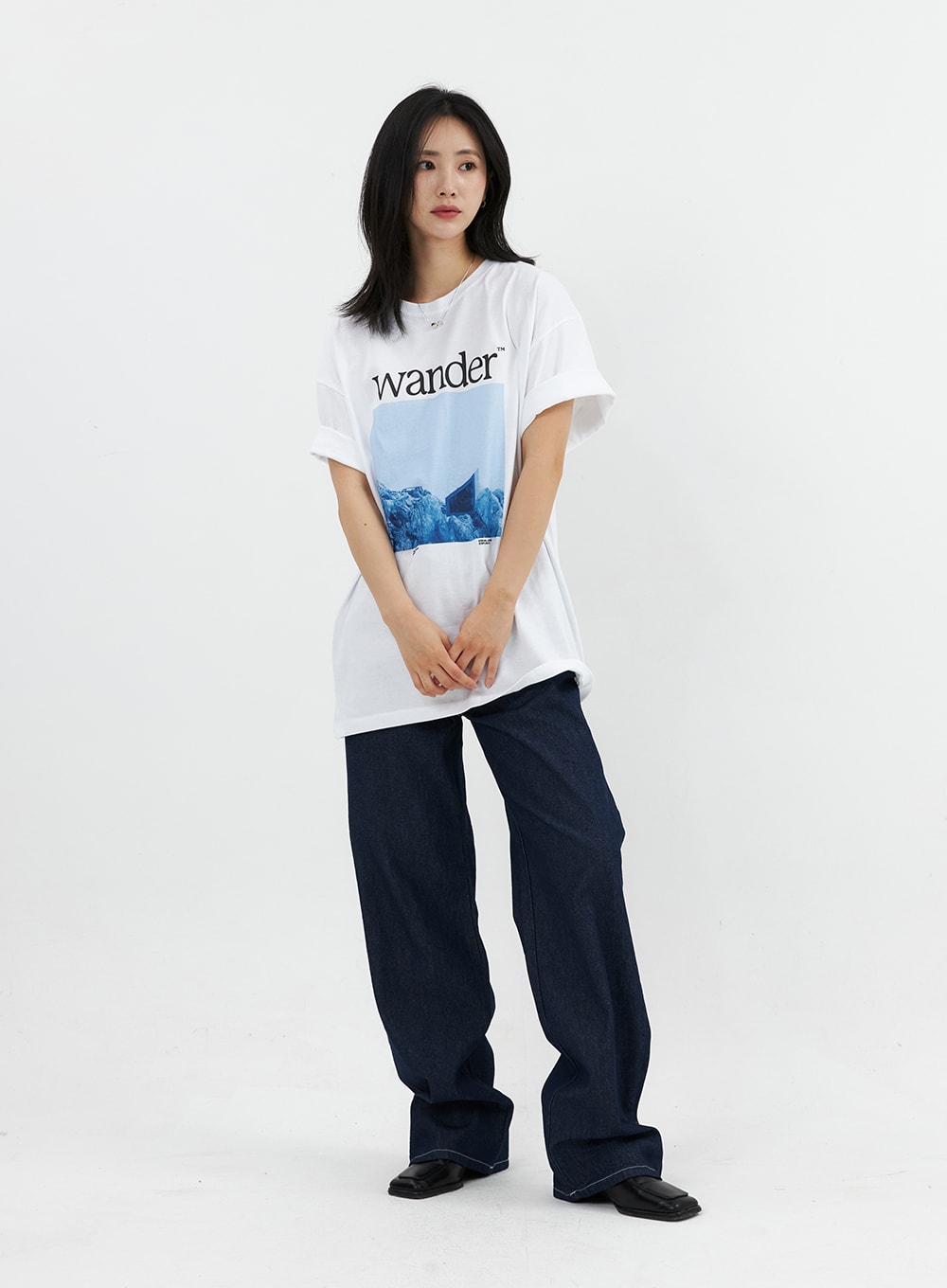 Stitched Jeans OO305 in Blue, front full-body on model, wide-fit dark indigo denim, contrast white stitching at seams, styled with oversized white graphic tee.