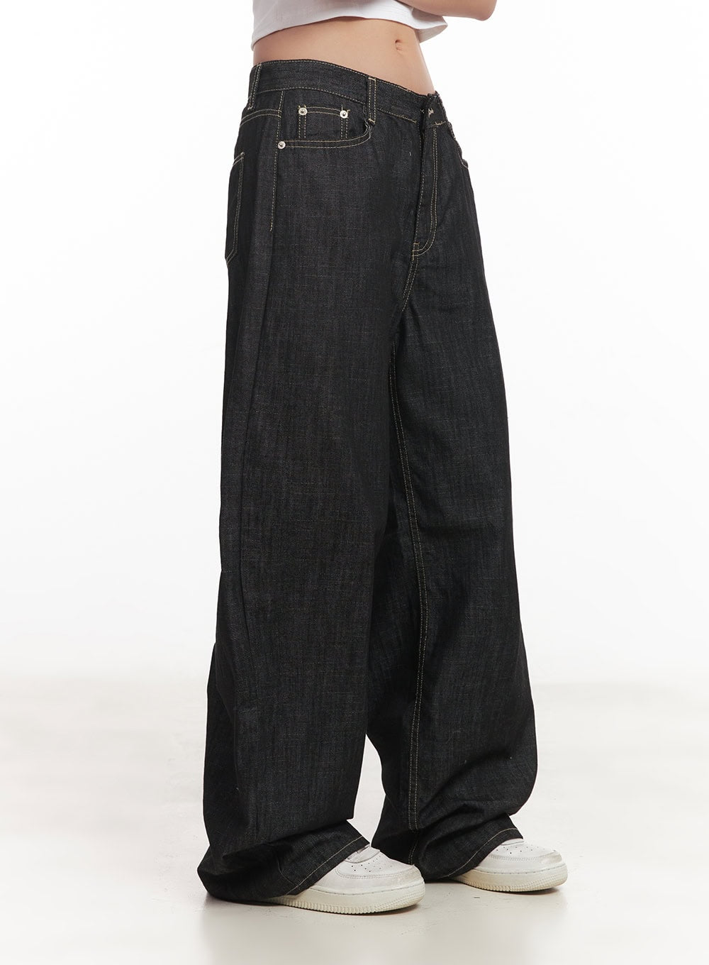Fenna Baggy Jeans CA529 in black, close-up side shot, highlighting low-rise fit, coin pocket, contrast stitching, and voluminous wide leg falling over sneakers.