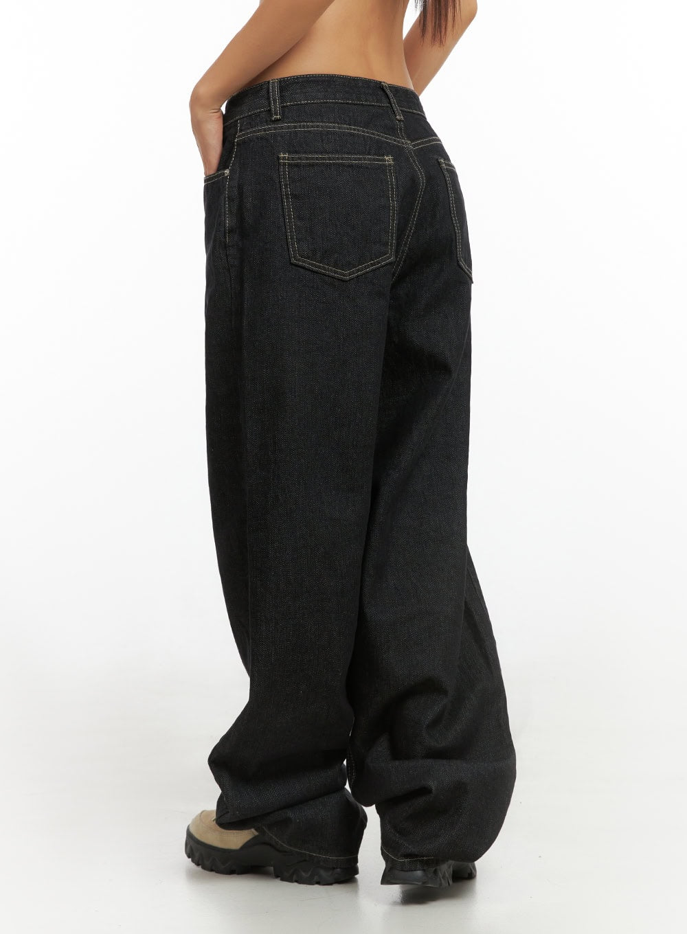 Clover Stitched Baggy Jeans IS402 in black, rear 3/4 close-up on model, highlighting back patch pockets with contrast topstitching, wide baggy silhouette, and stacked hem over boots.