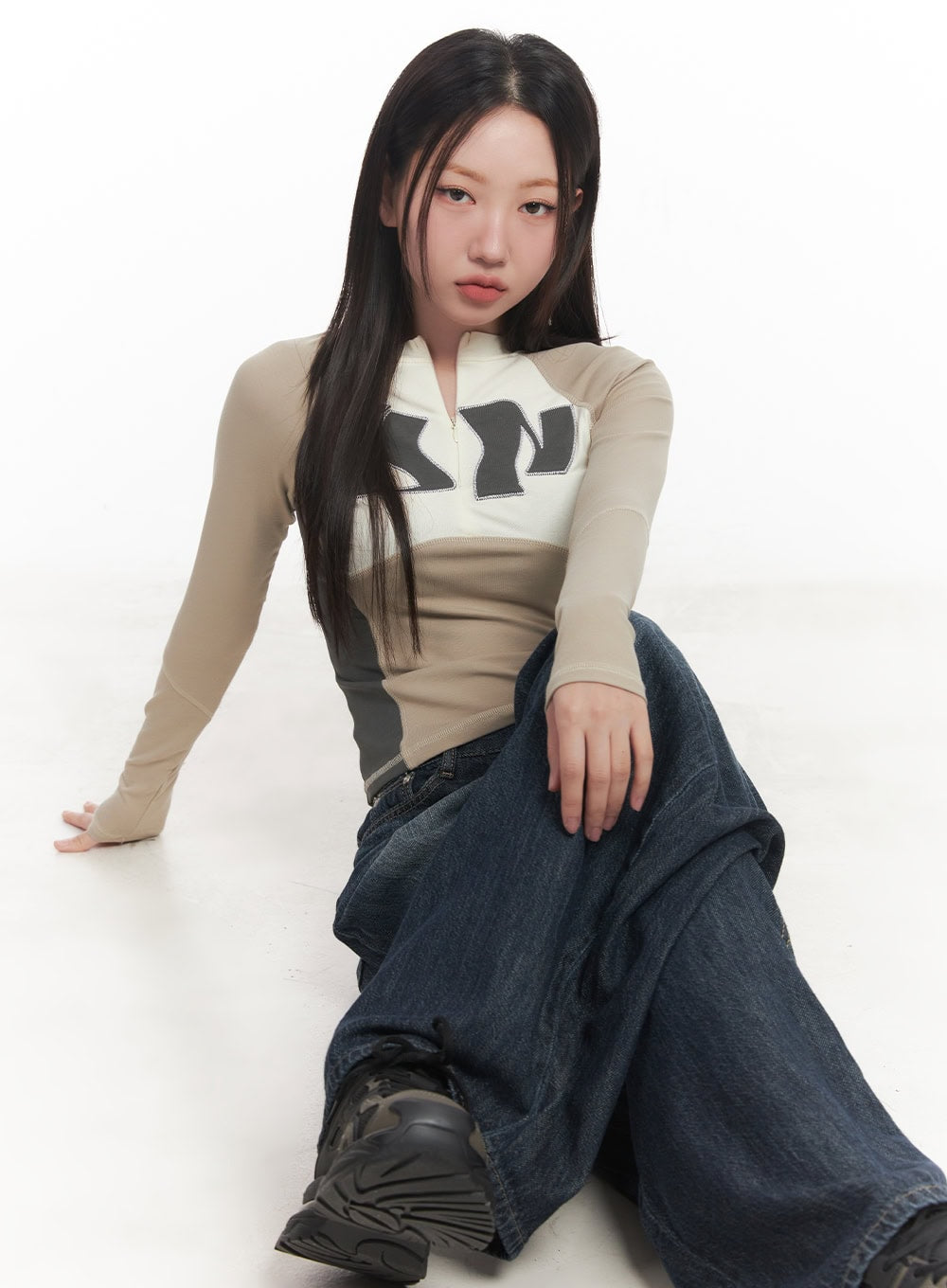 Renna Baggy Jeans CA521 in dark blue, seated floor-level editorial shot on model, relaxed wide-fit washed denim bunching at ankles, street acubi style.