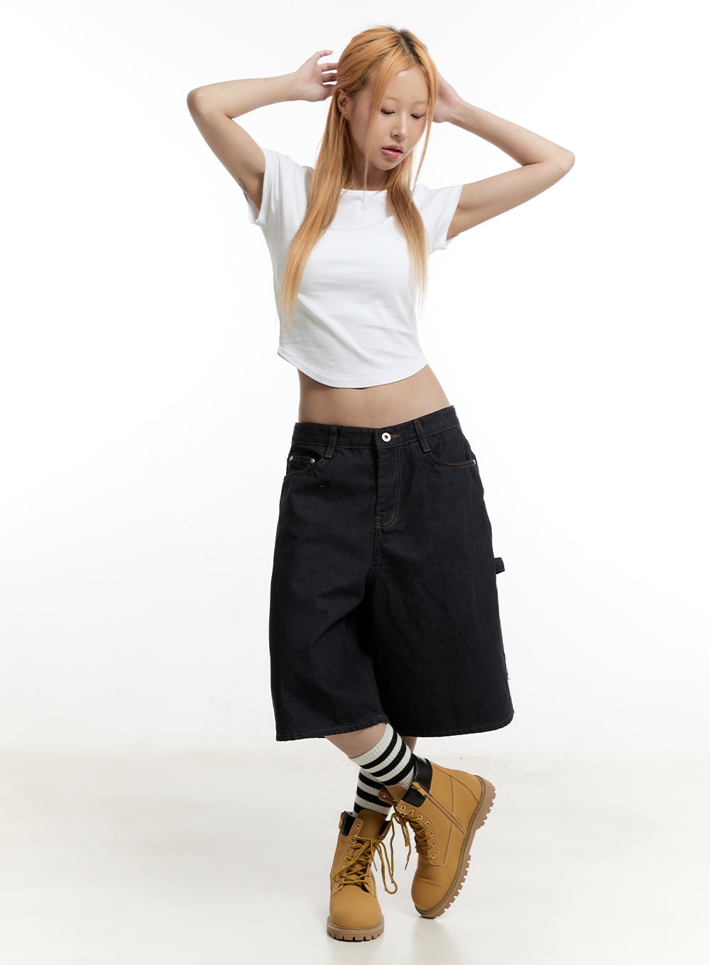 Carpenter Denim Wide-Leg Jorts CY501 in dark blue, full-body front shot on model with hands in hair, wide-fit midi denim paired with white crop tee, striped socks, and tan boots.