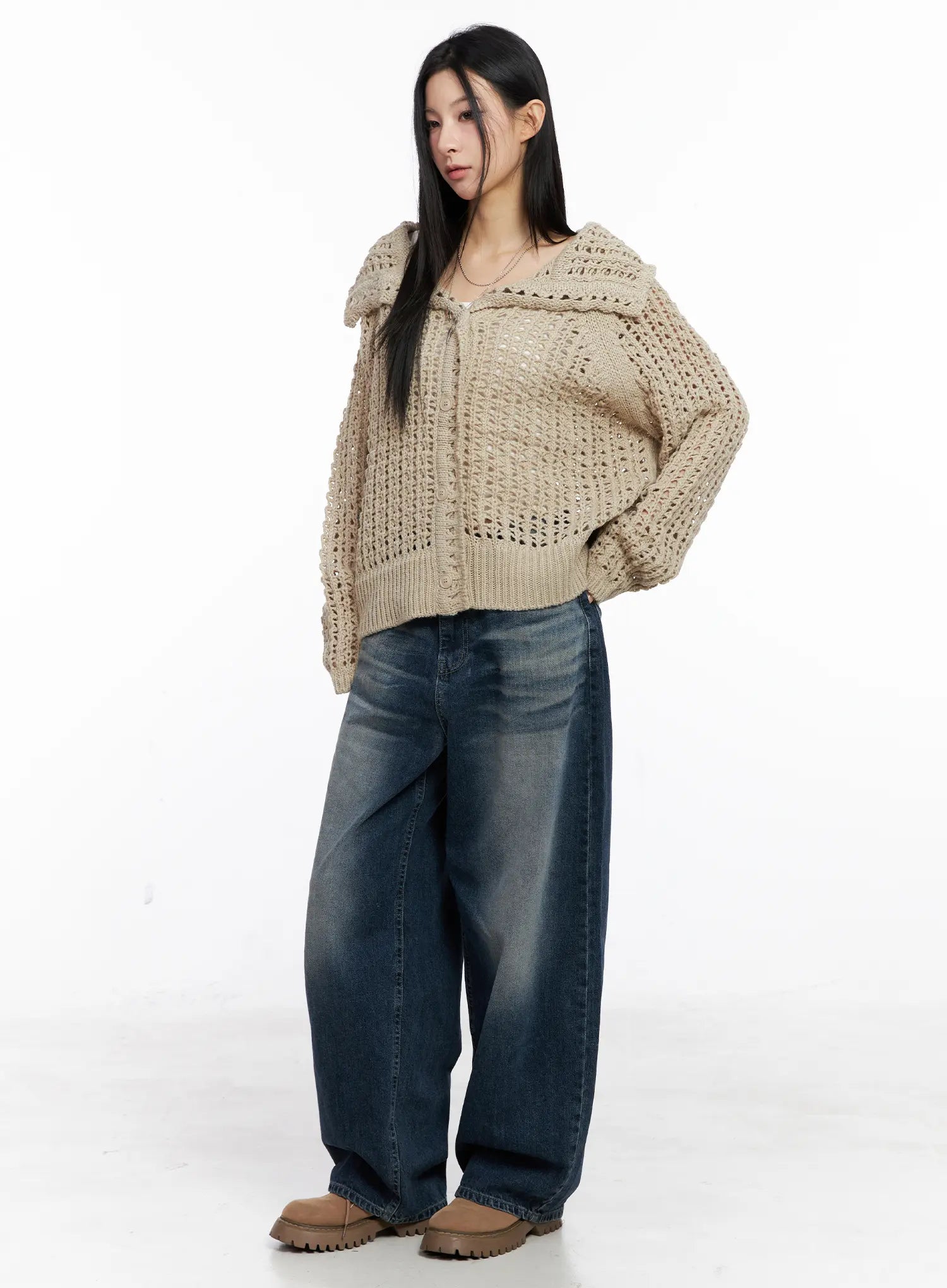 Aisha Washed Baggy Jeans CC1109 in mid blue, front three-quarter view on model, relaxed wide fit with washed finish, styled with beige open-knit hooded cardigan and chunky boots.