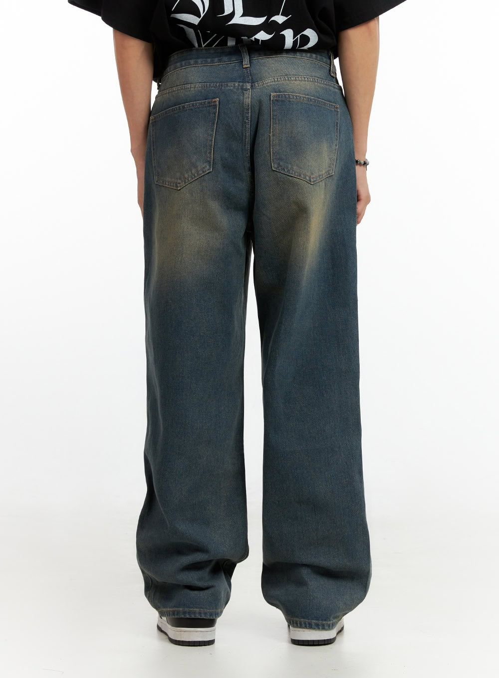 Men's Vintage Washed Loose Fit Jeans (Dark Blue) IG402, back view close-up on model, dual back pockets with yellow-tinted vintage wash fading, wide loose leg, paired with graphic black tee.