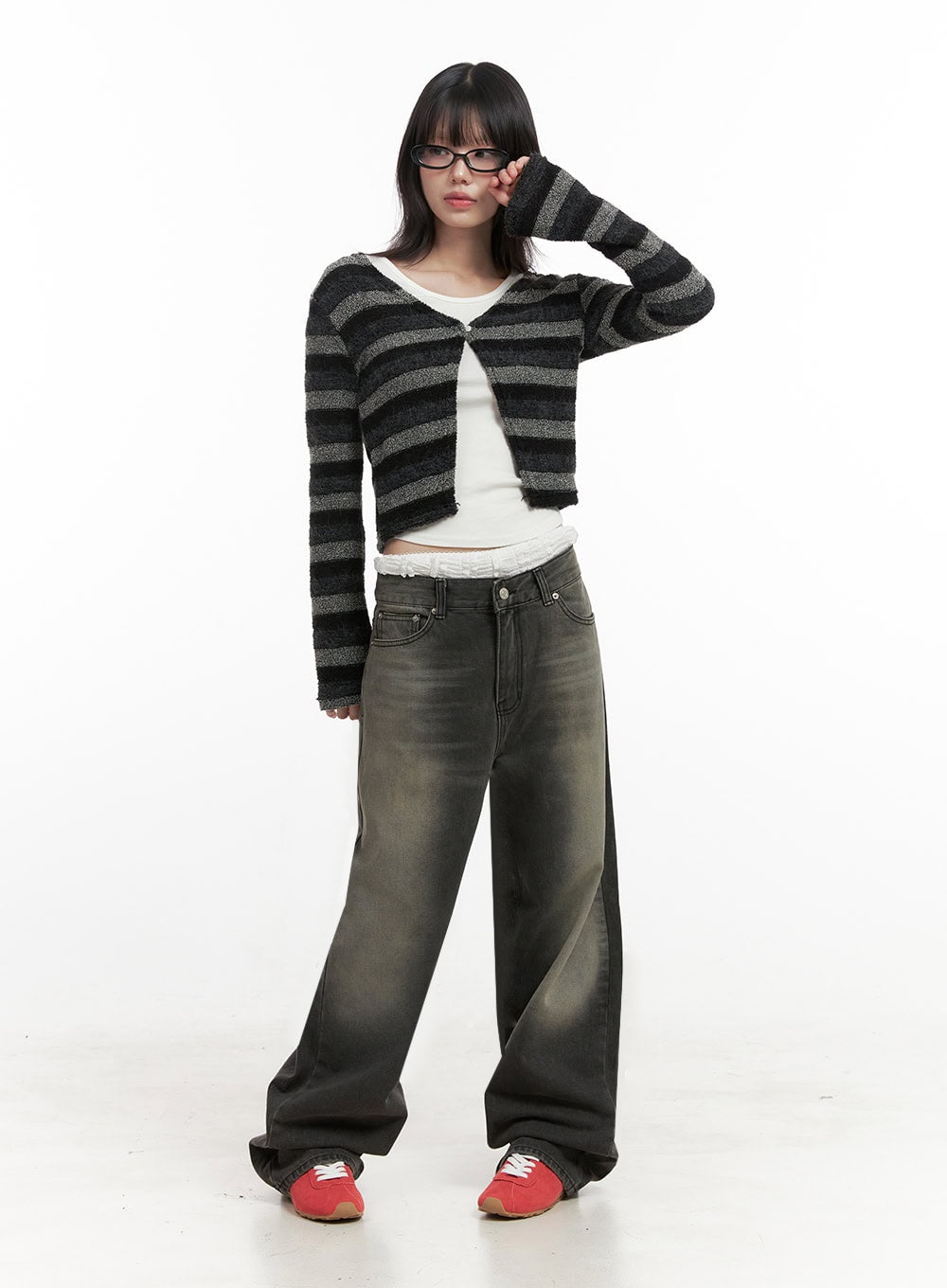 Matilda Wide-Fit Baggy Jeans ID402 in black, full-body angled front shot on model, washed wide-fit denim, hand raised to face pose, paired with stripe cardigan and red sneakers.