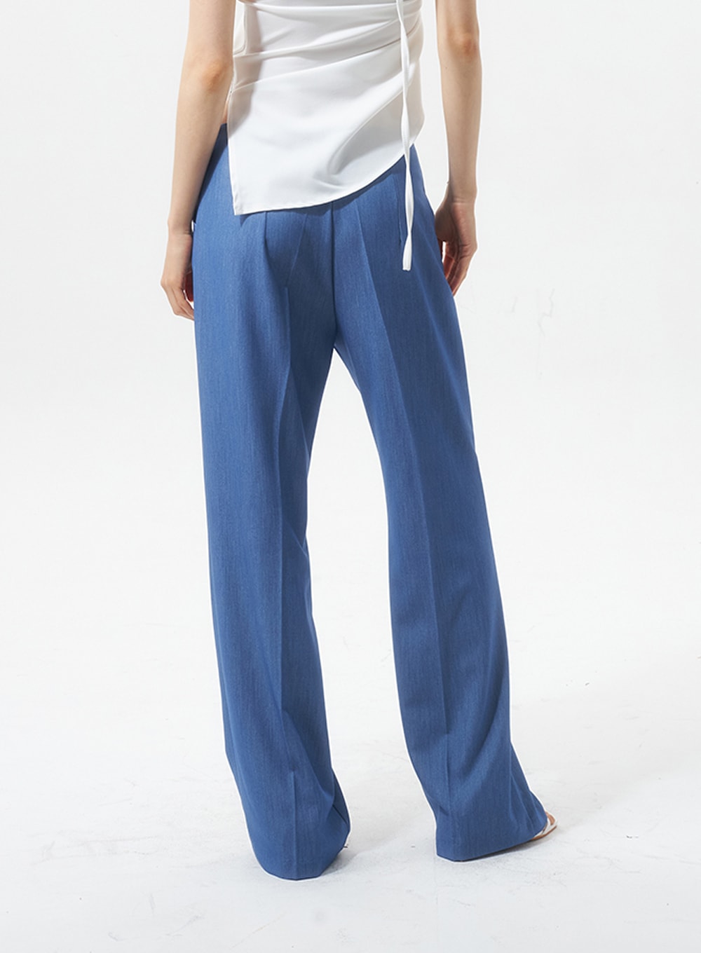 Low Rise Tailored Pants IU326 in blue, back view close-up on model, center back seam and wide-leg fall visible, smooth polyester-rayon fabric, styled with white halter top.