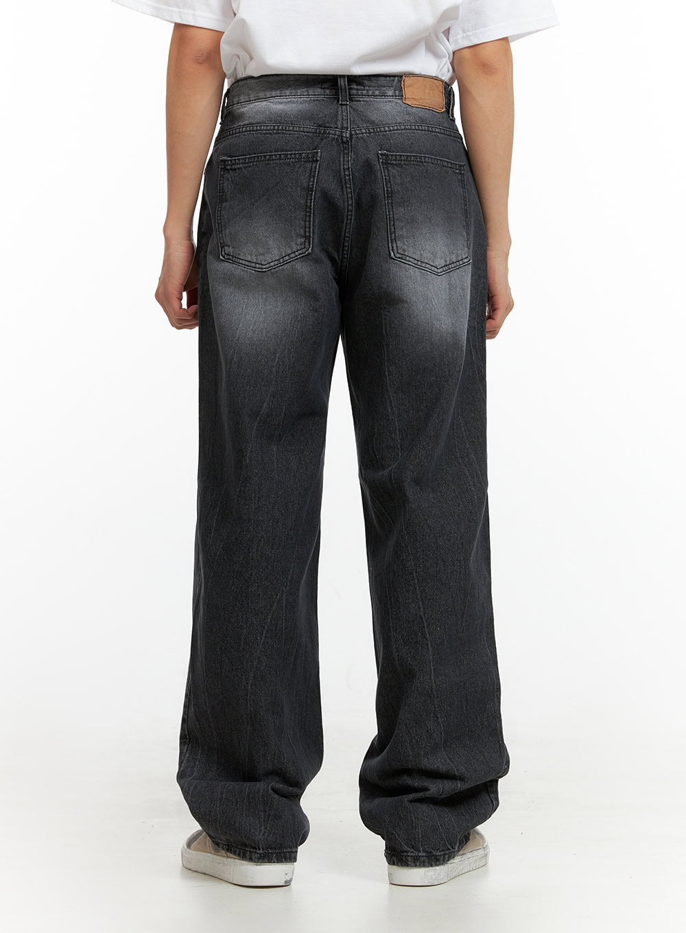 Men's Loose Fit Straight Jeans IU412 in washed black, back view close-up on model, dual back pockets with tan leather patch, faded wash detail across seat and thighs, wide straight hem.